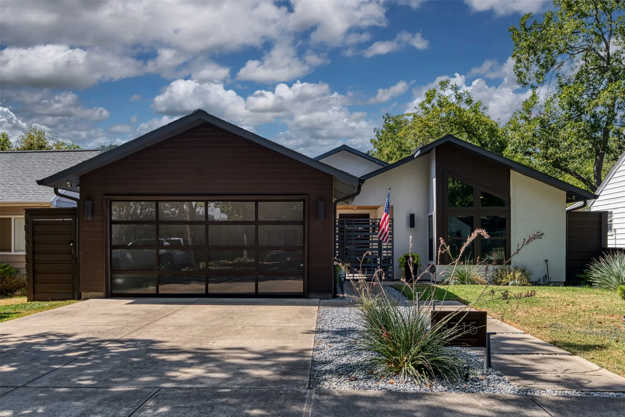 Contemporary exterior featuring a panel-style garage door, dark wood siding, and an angular window design