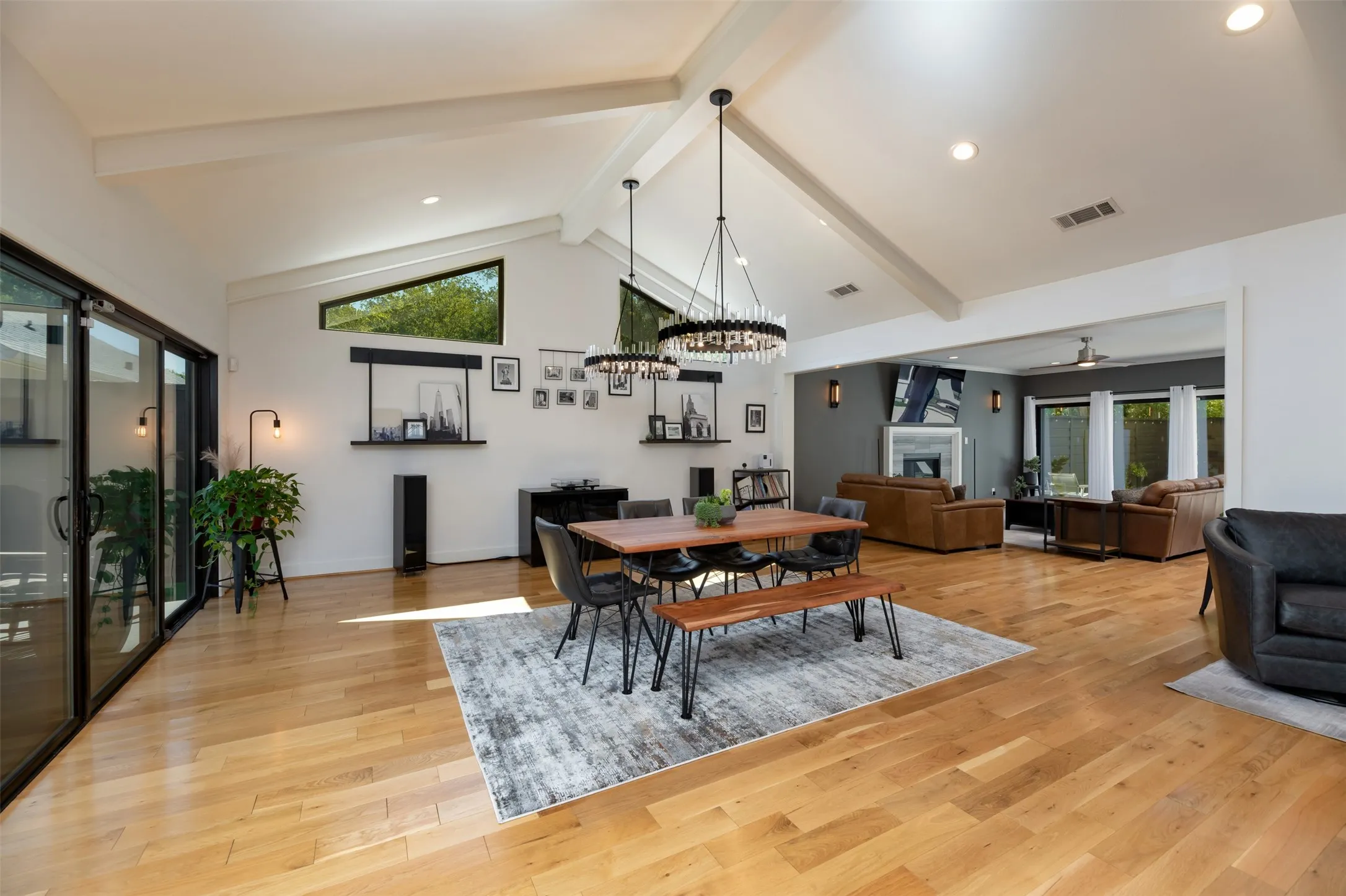 Vaulted ceilings with exposed beams, hardwood flooring, recessed lighting, and large sliding glass doors
