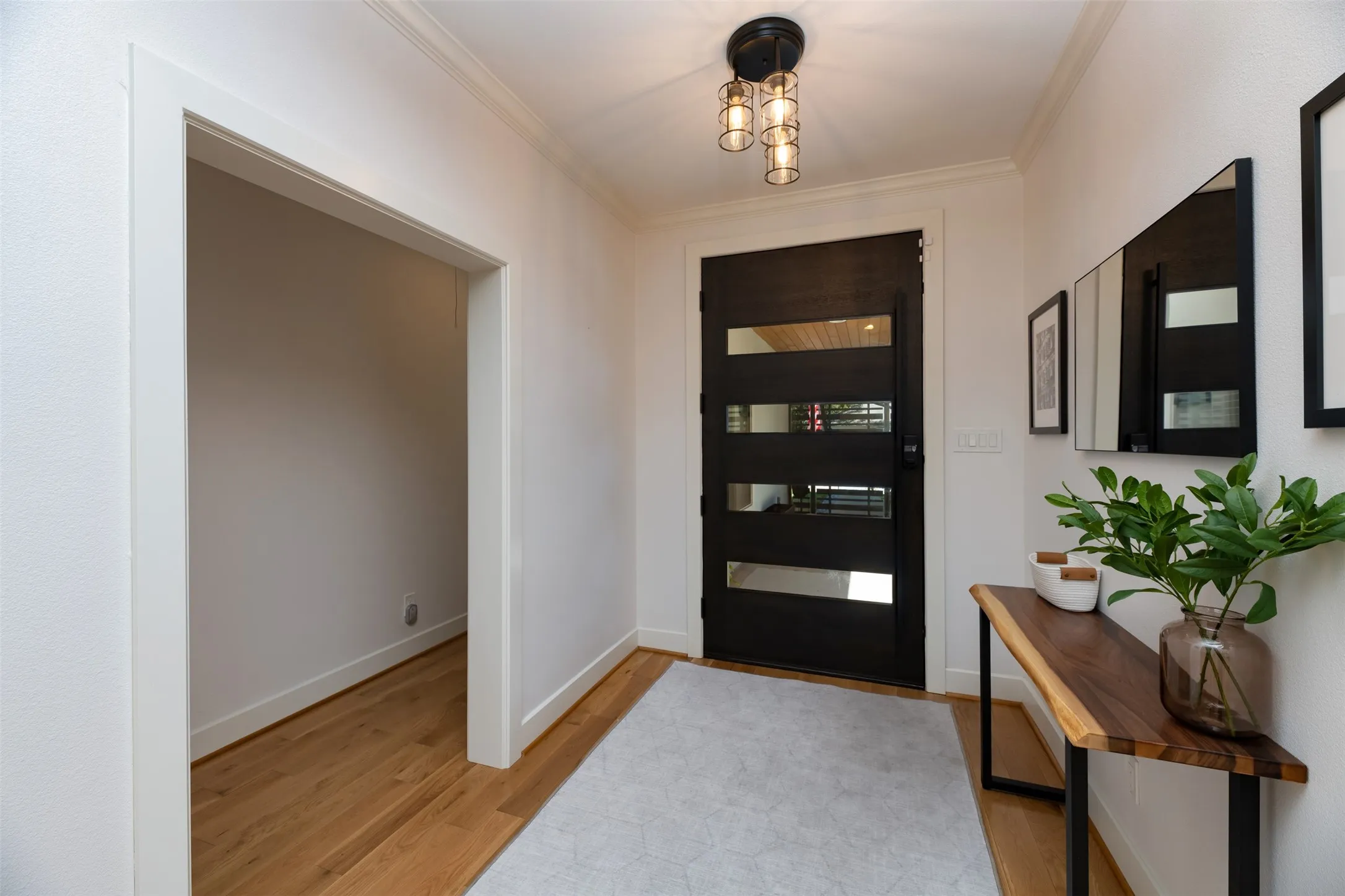 Entryway featuring a modern door with horizontal glass panels, crown molding, wood-finish flooring, and a contemporary semi-flush mount light fixture