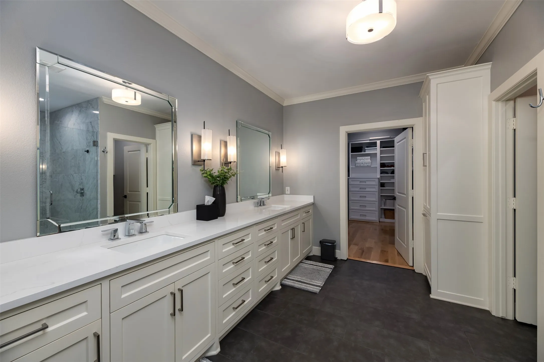 Dual vanity with white cabinetry, polished chrome fixtures, and a large framed mirror