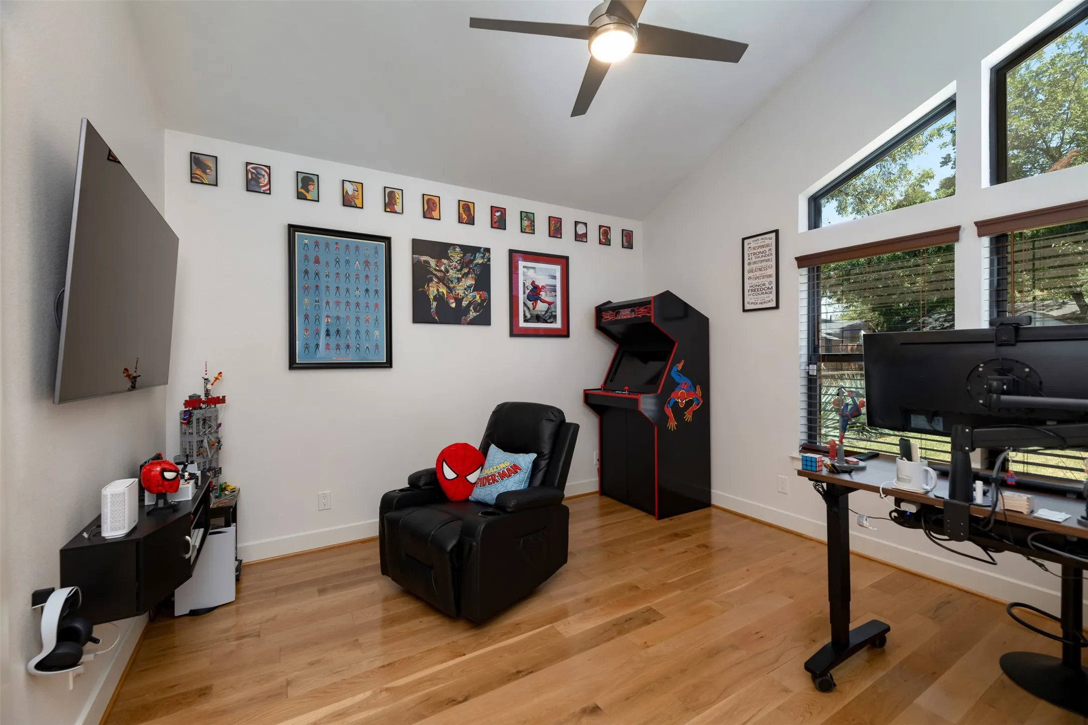 Vaulted ceiling with a ceiling fan, wood-finish flooring, and large windows with horizontal blinds