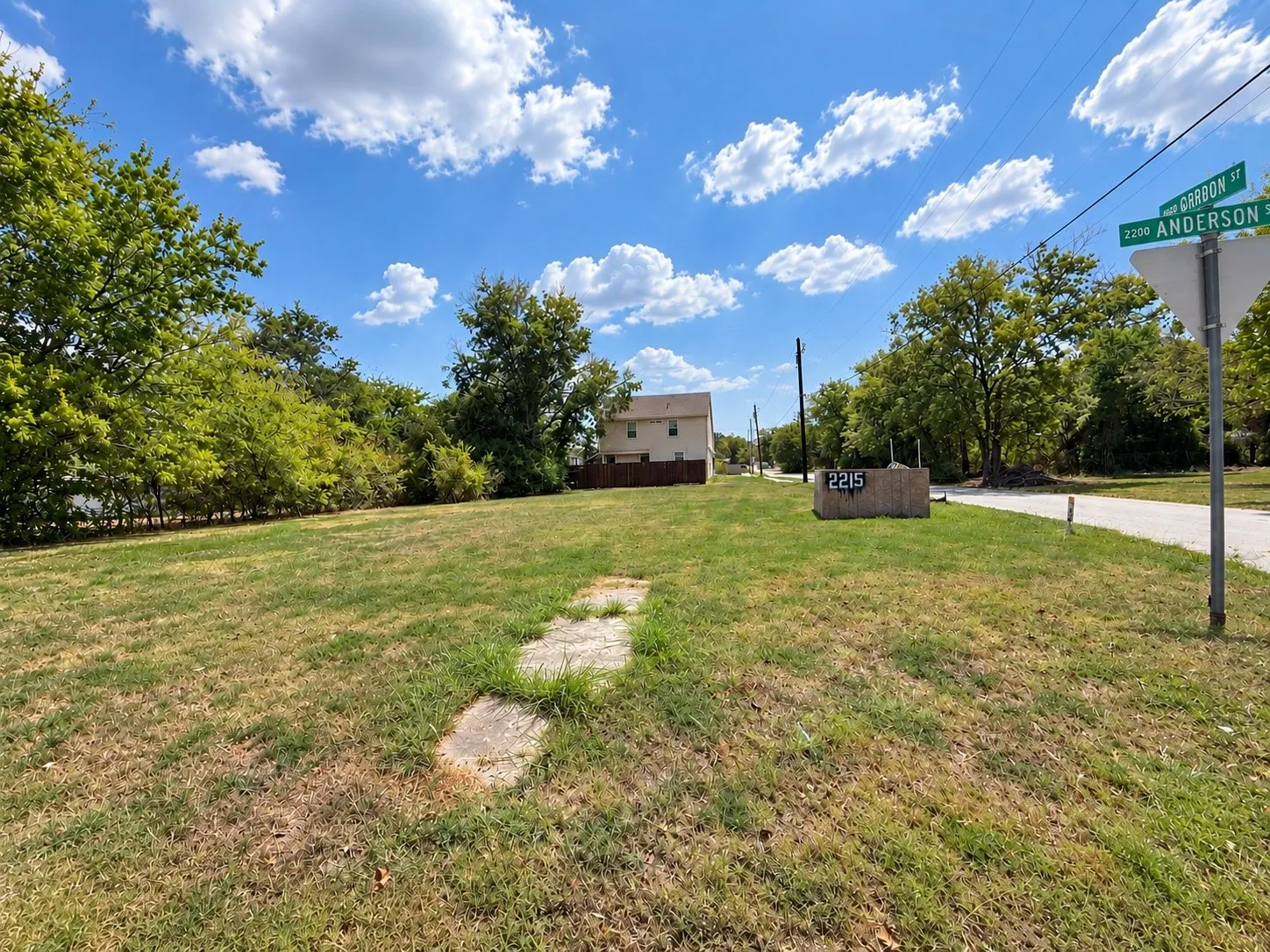 Expansive lot featuring a grass lawn, mature trees, and a street sign indicating Gordon and Anderson Streets
