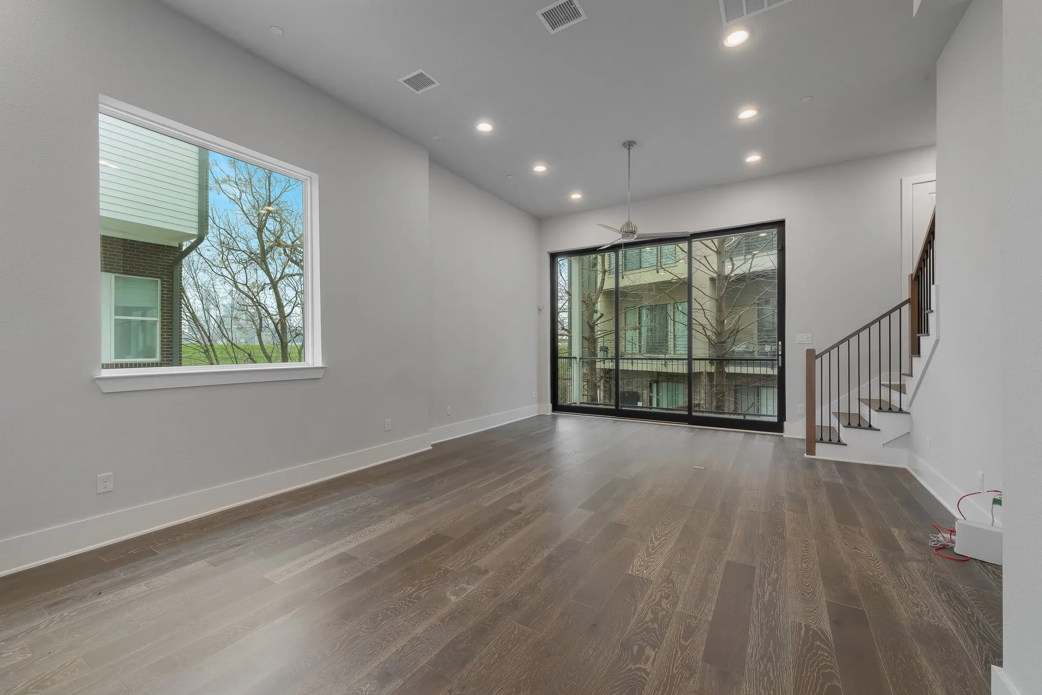 Unfurnished living room with baseboards, wood finished floors, visible vents, and stairs