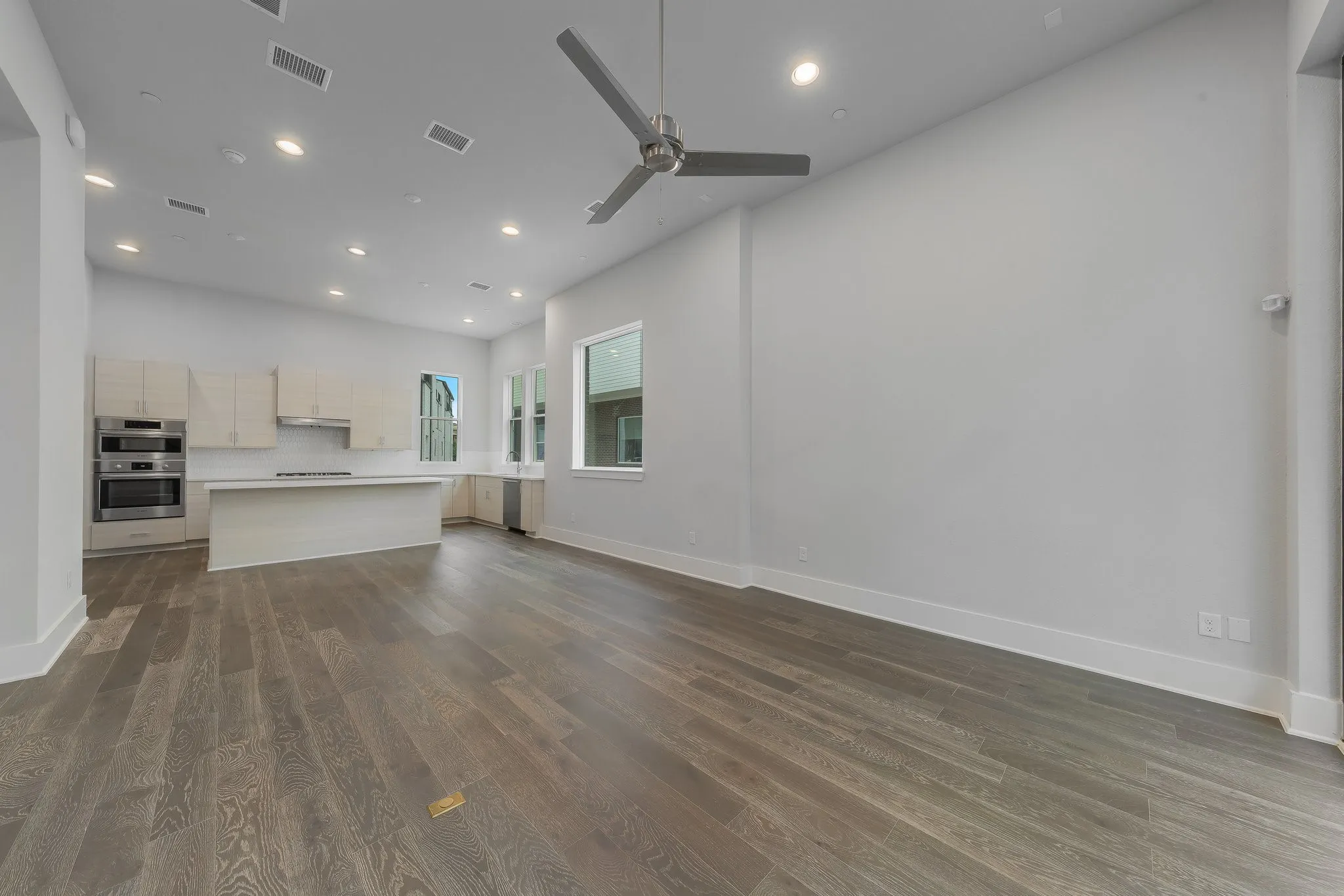 Unfurnished living room featuring a ceiling fan, dark wood-type flooring, visible vents, and recessed lighting