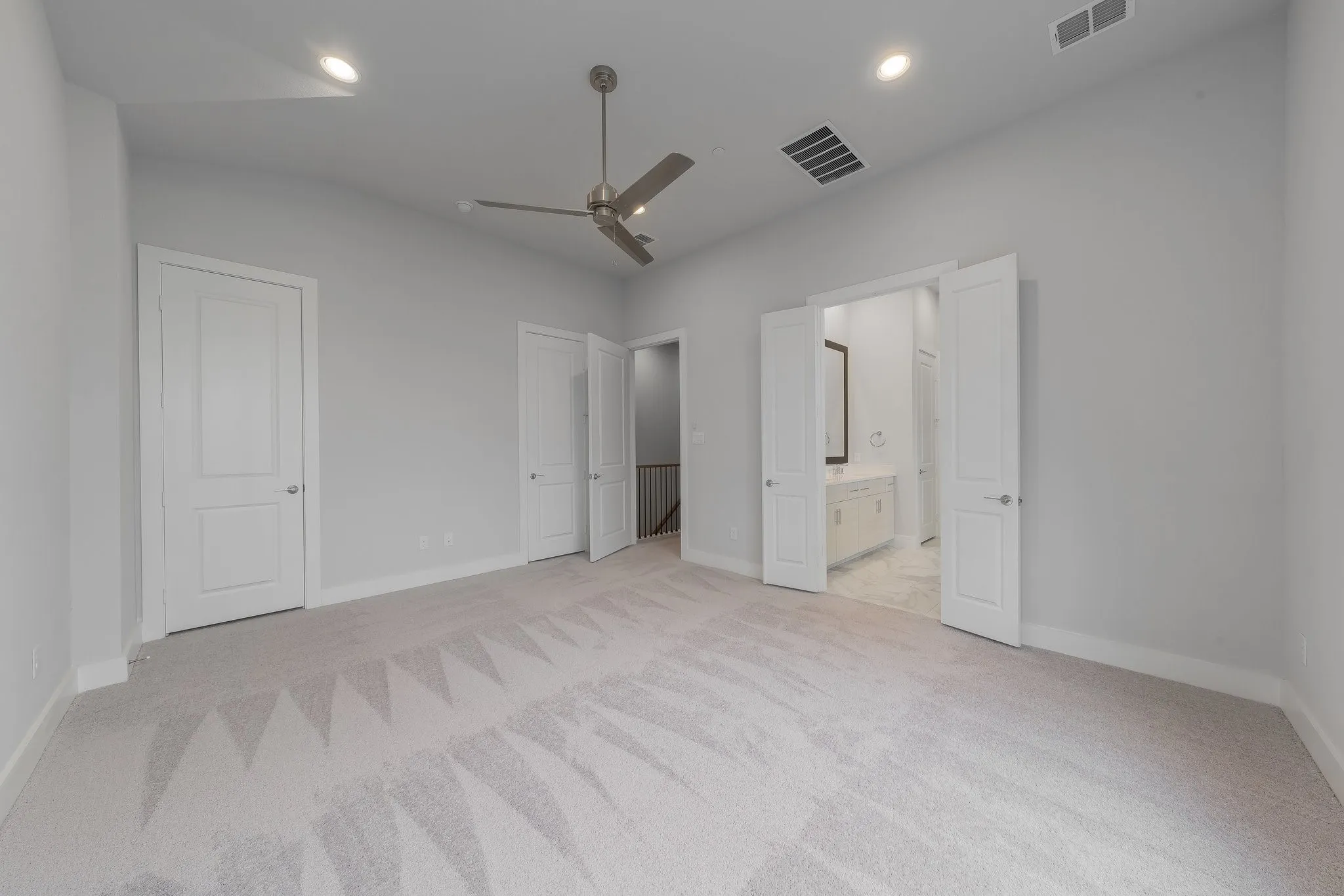 Unfurnished bedroom featuring visible vents, baseboards, light carpet, and connected bathroom