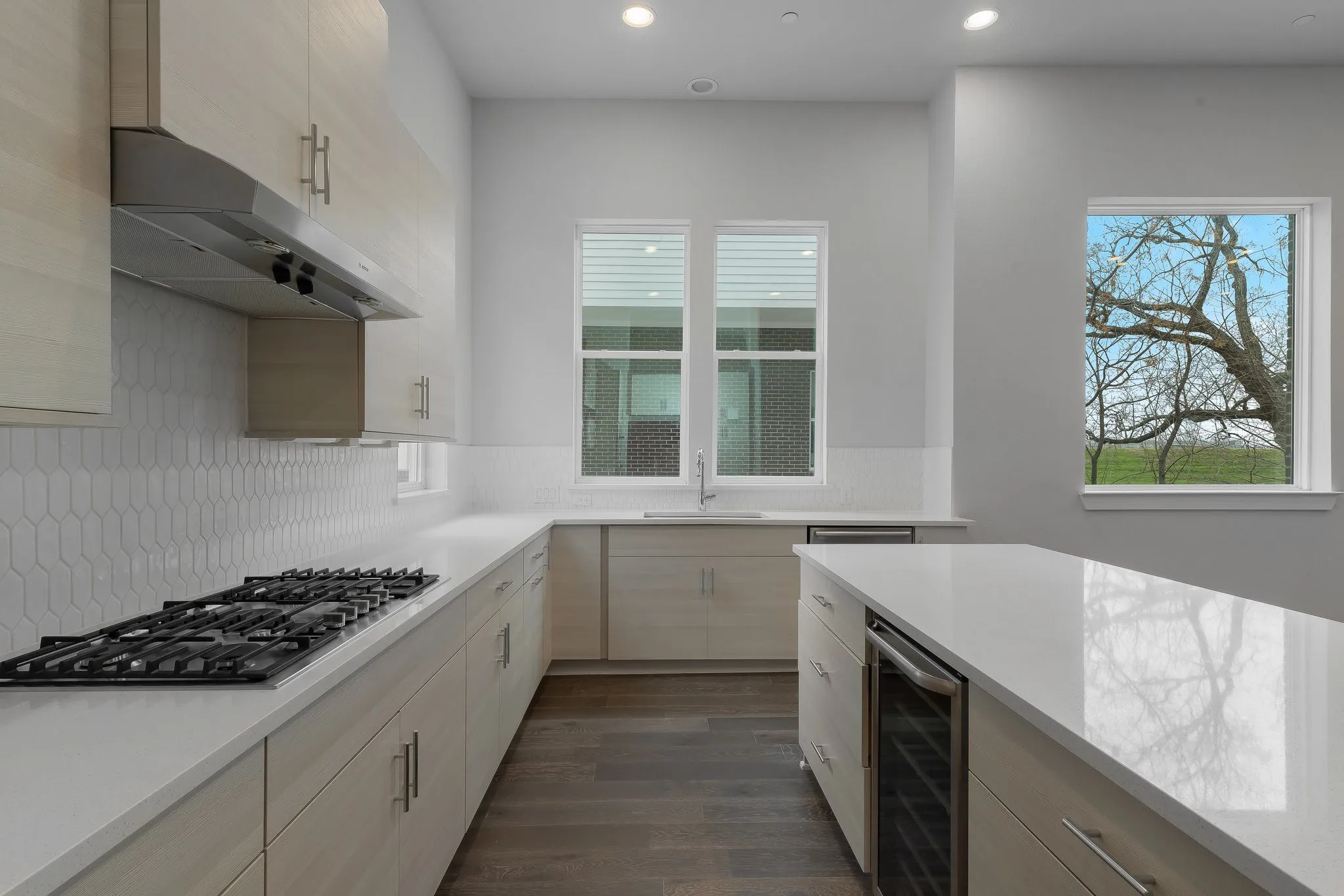 Kitchen featuring stainless steel gas cooktop, a healthy amount of sunlight, beverage cooler, and exhaust hood