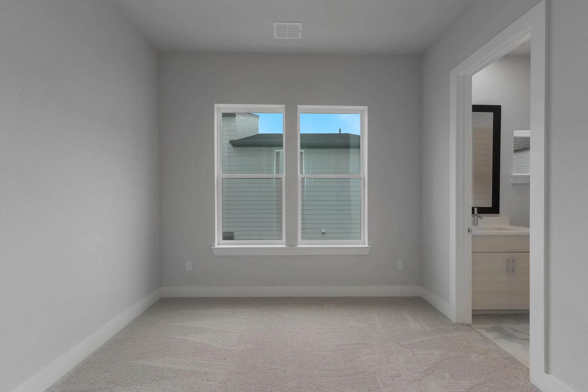 Unfurnished bedroom featuring light colored carpet, baseboards, connected bathroom, and visible vents