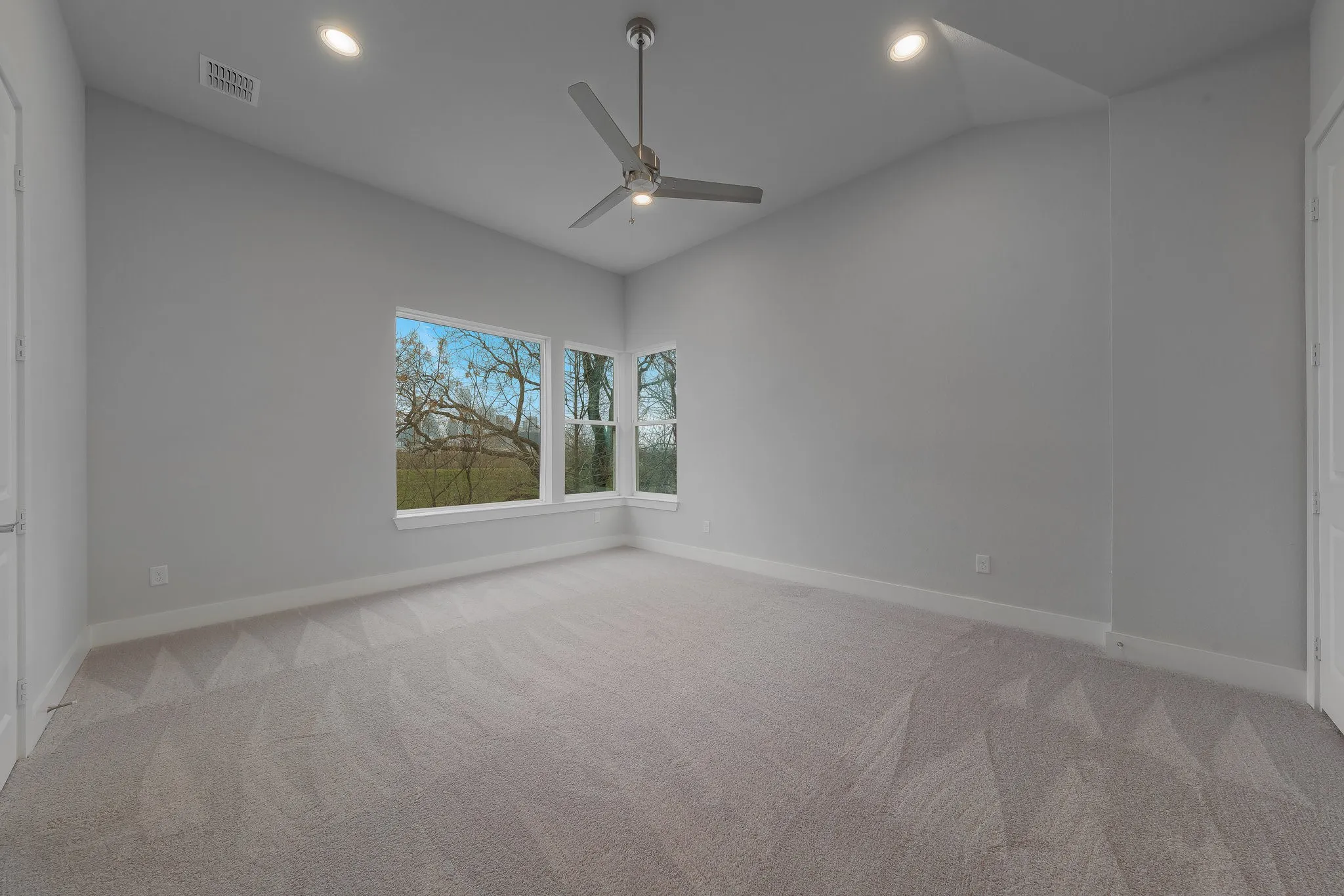 Spare room with vaulted ceiling, a ceiling fan, visible vents, and carpet