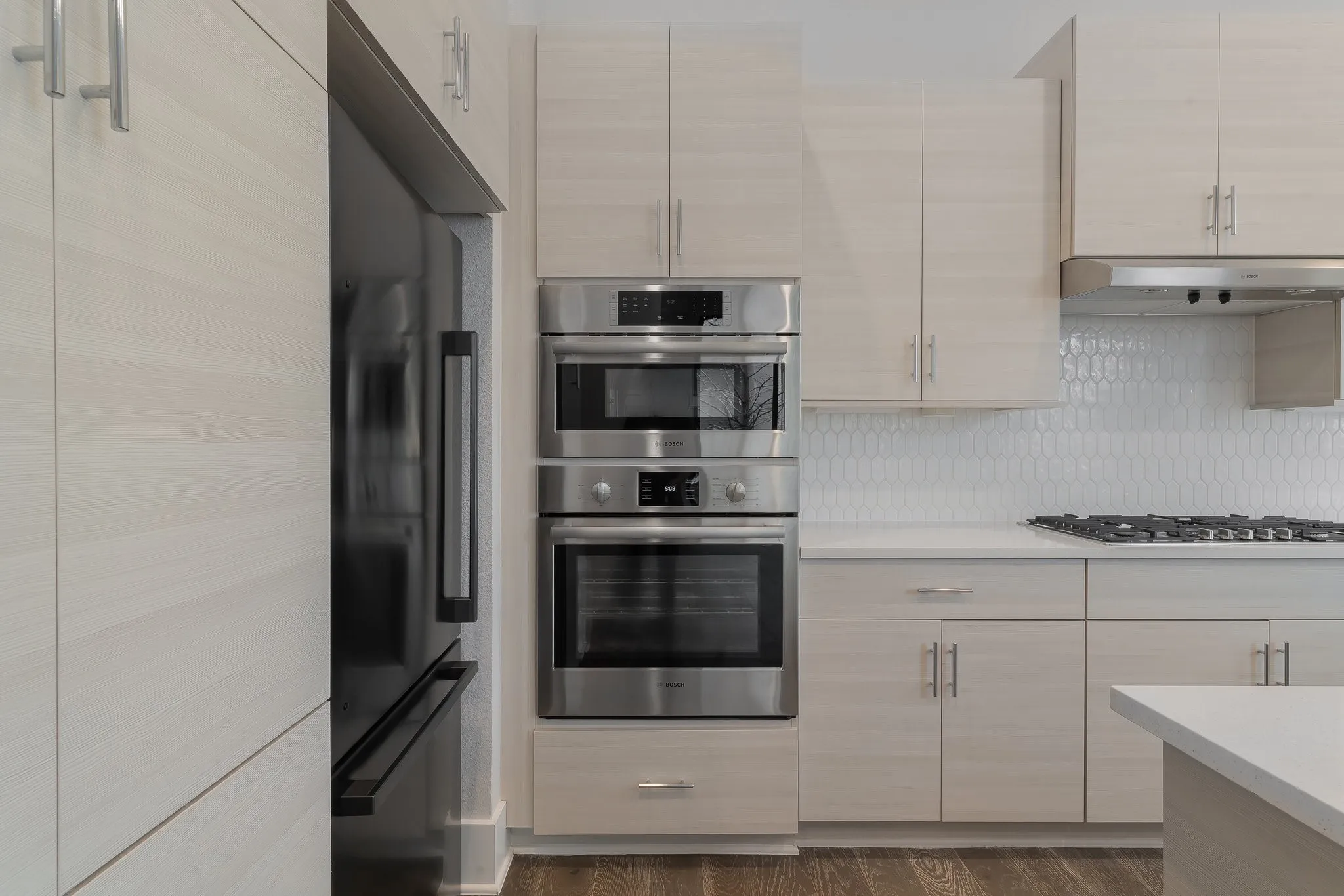 Kitchen with light countertops, backsplash, under cabinet range hood, and stainless steel appliances