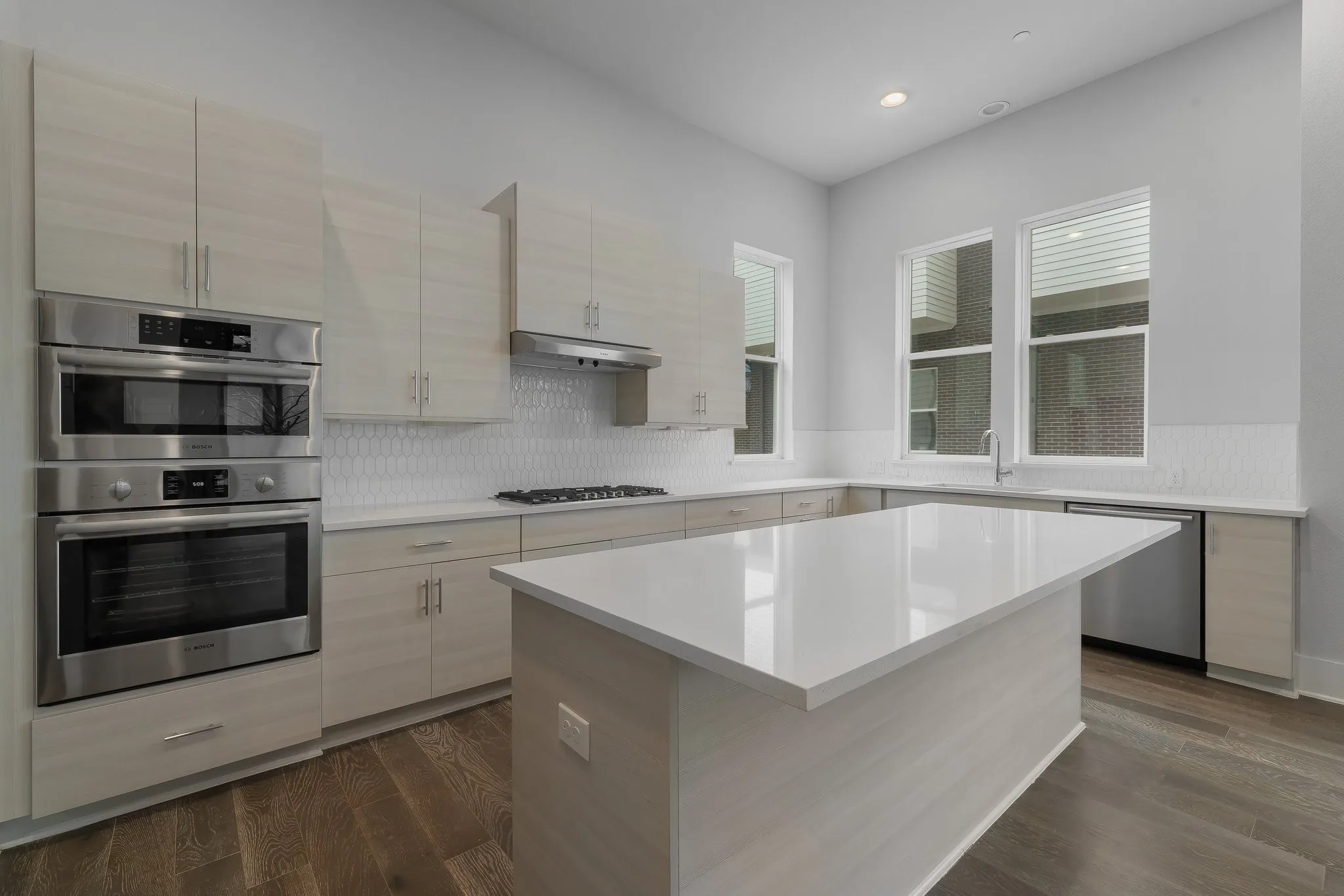Kitchen with a sink, appliances with stainless steel finishes, light countertops, under cabinet range hood, and recessed lighting