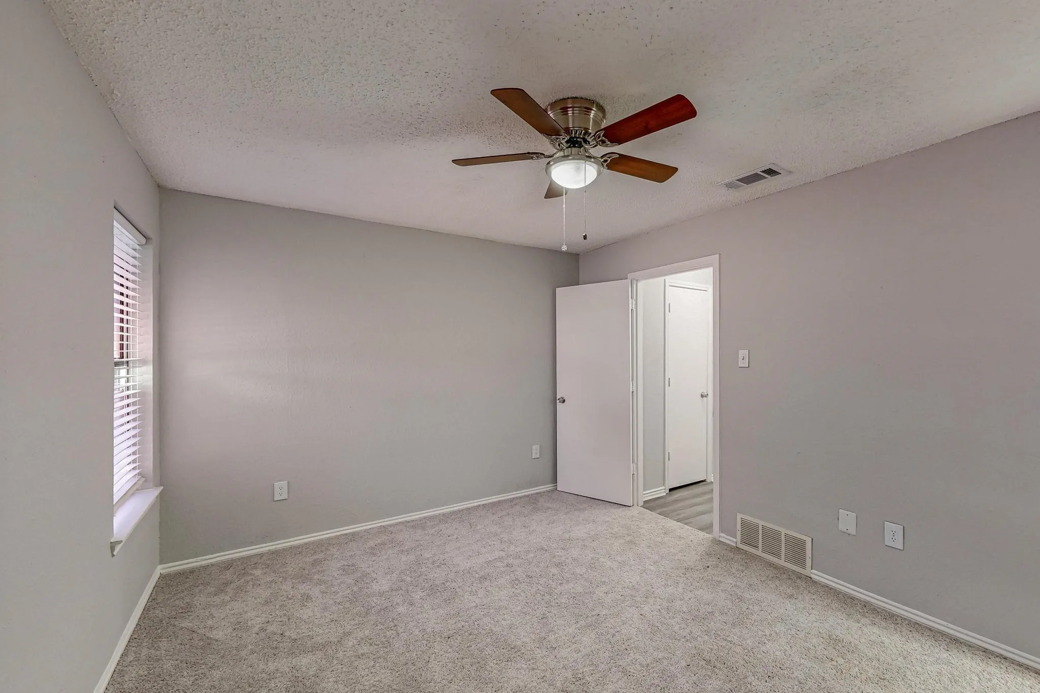 Carpeted room featuring a ceiling fan with integrated lighting, a window with blinds, and light gray walls
