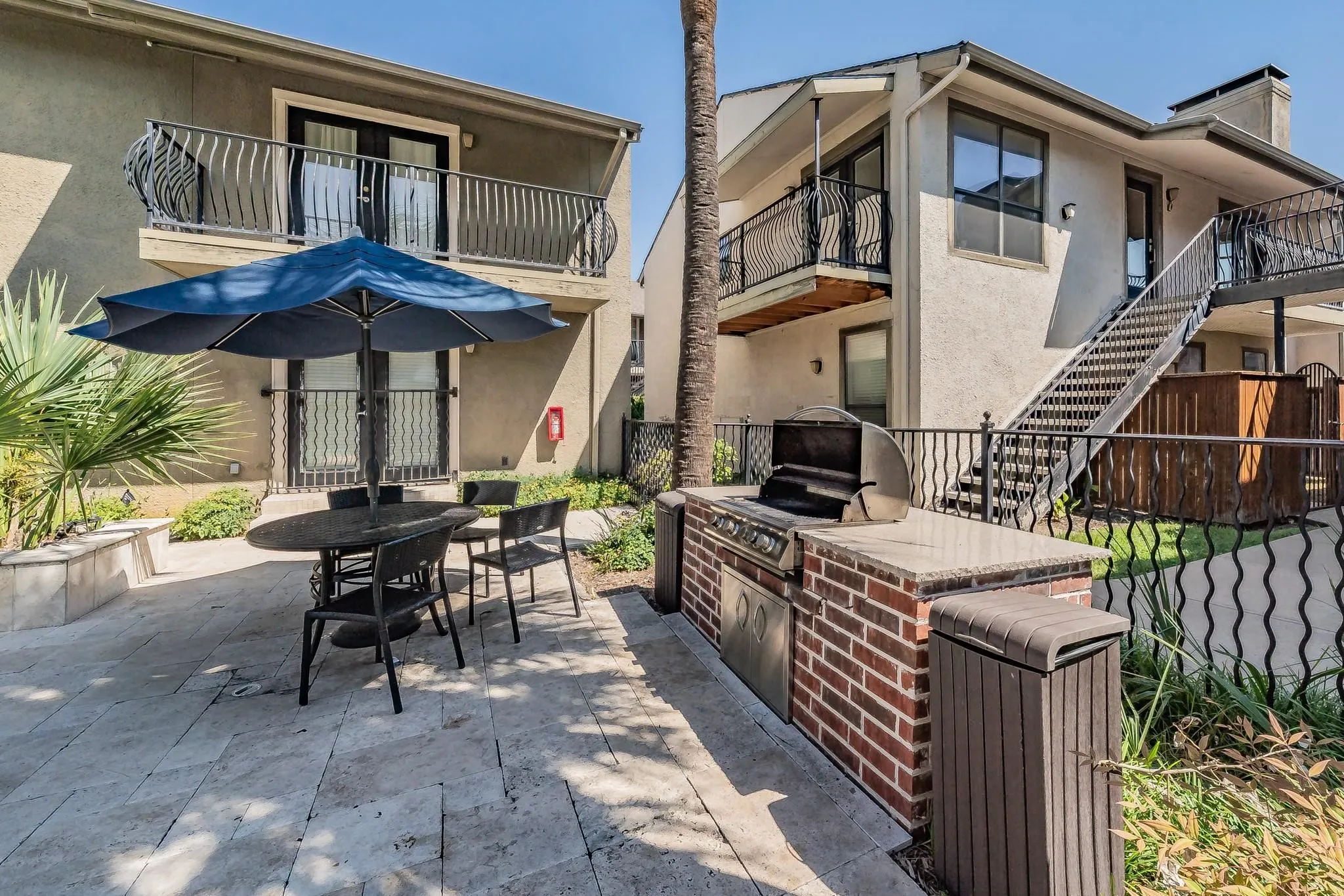 Outdoor patio with stone tile flooring, built-in brick BBQ, and black wrought iron railings