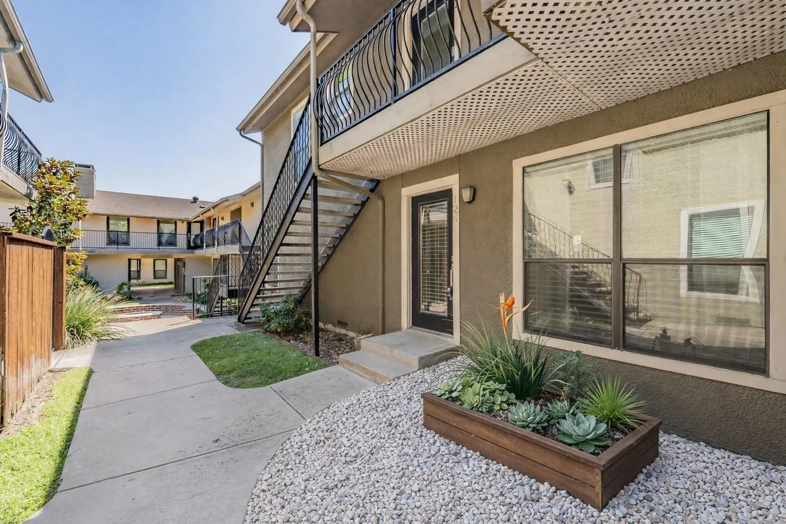 Exterior entry featuring a wood-finish planter with succulents, large window, and opaque glass door