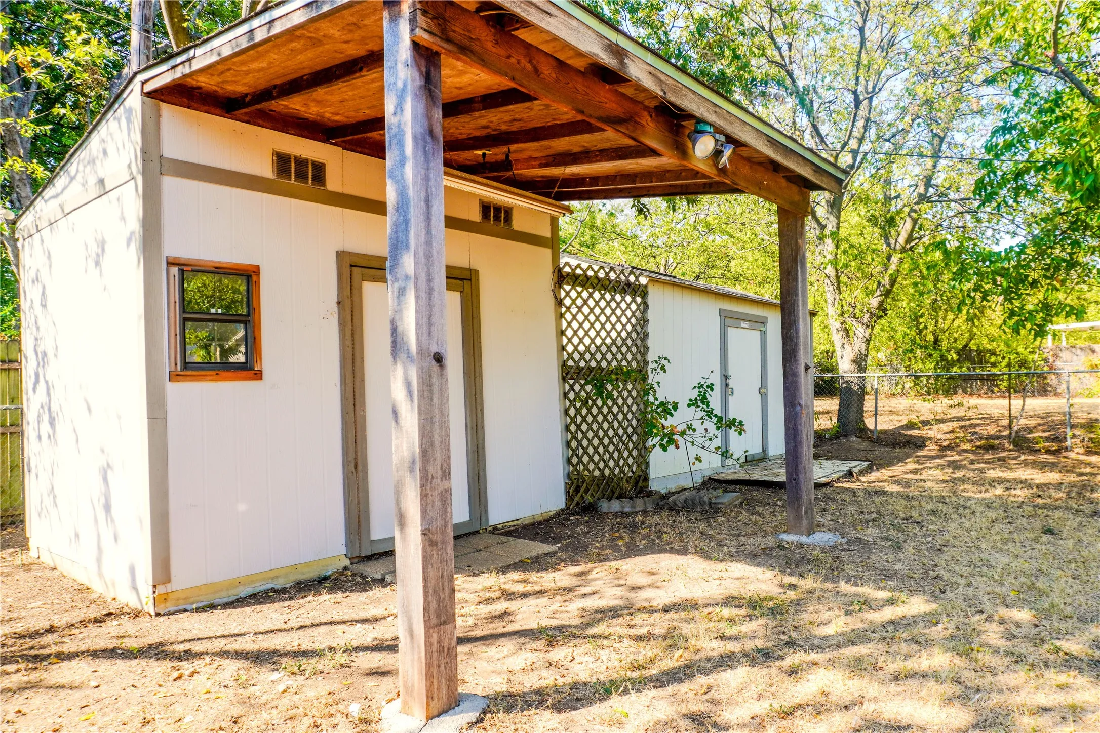 Accessory structure featuring a covered porch with exposed wood beams, a single window, and two doors