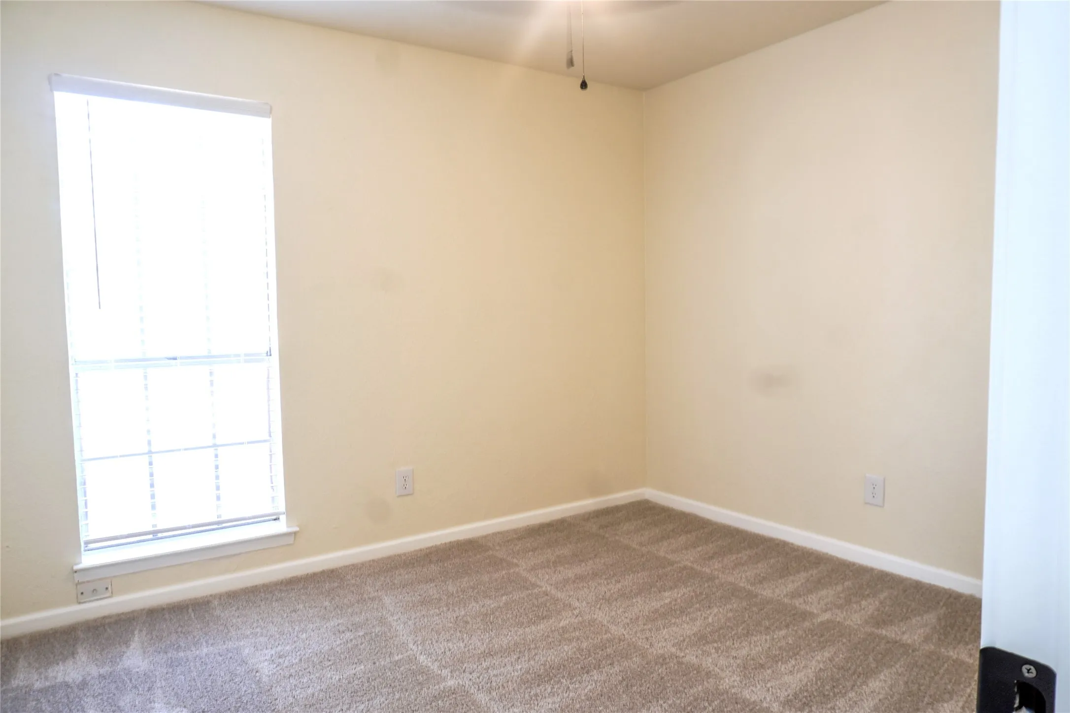 Carpeted flooring, neutral wall tones, window with horizontal blinds, and a ceiling-mounted light fixture