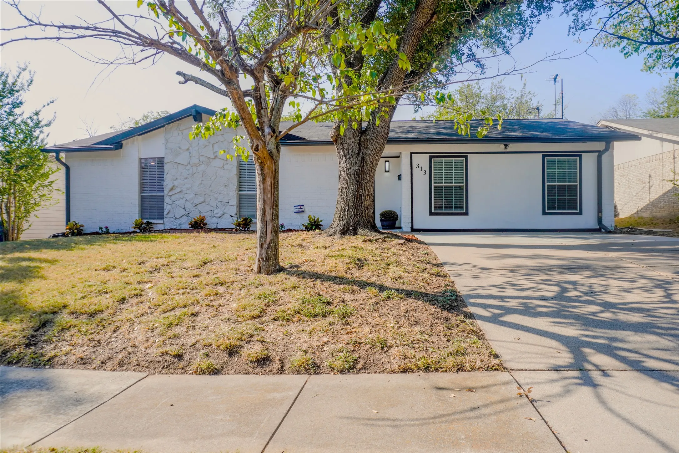 White exterior with stone accents, black window trim, and a concrete driveway