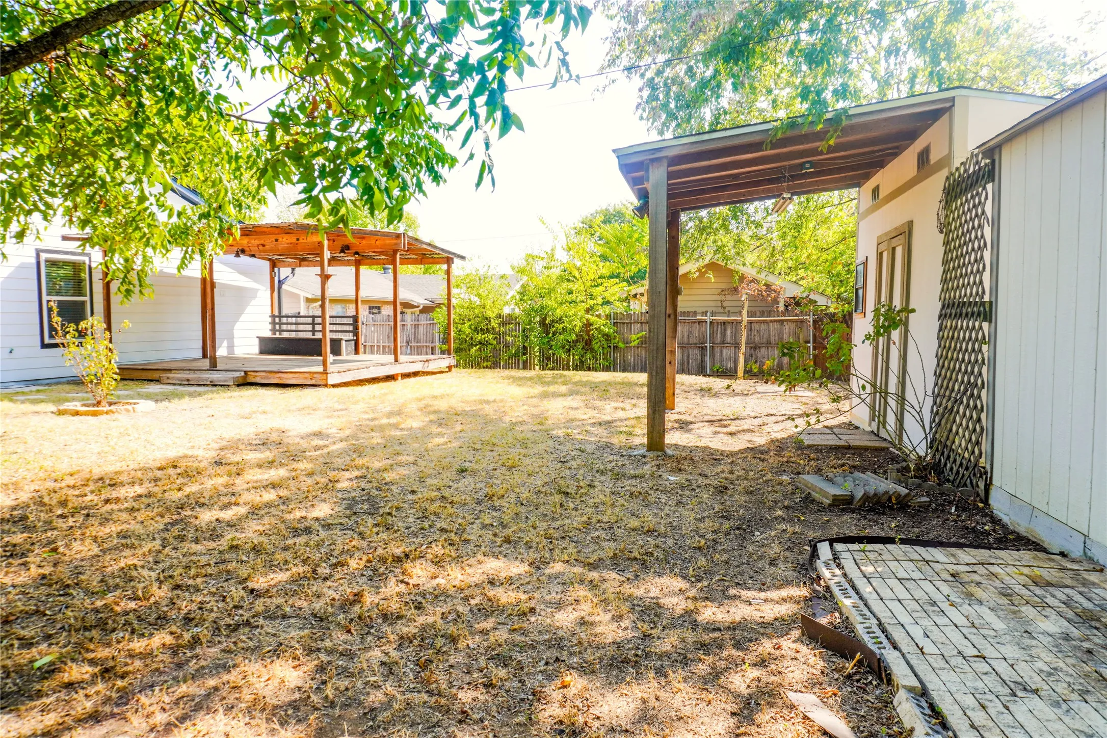 Expansive outdoor living area featuring a wooden deck, a covered patio structure, and a detached outbuilding