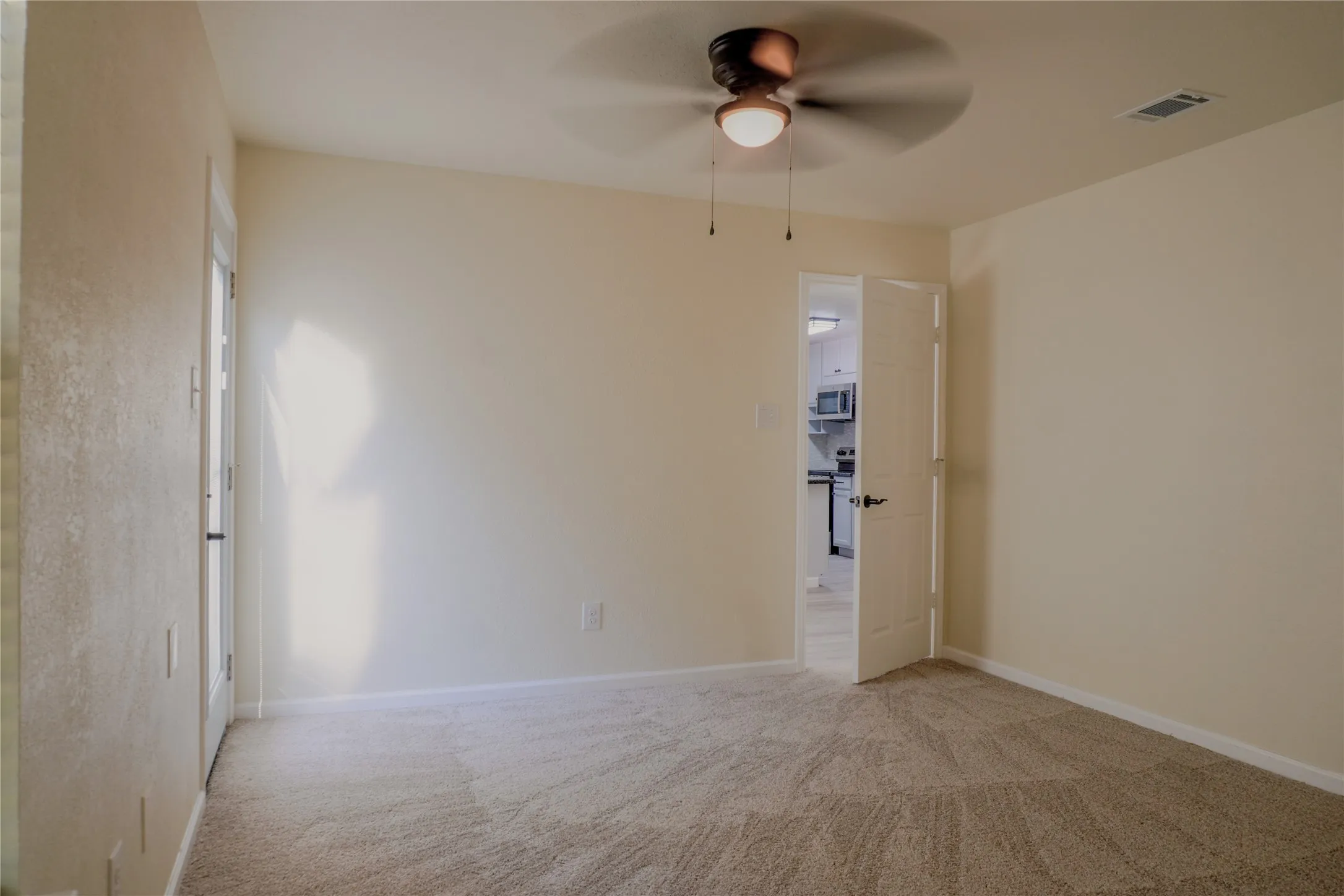 Carpeted room featuring a ceiling fan with integrated lighting, white baseboards, and a paneled interior door