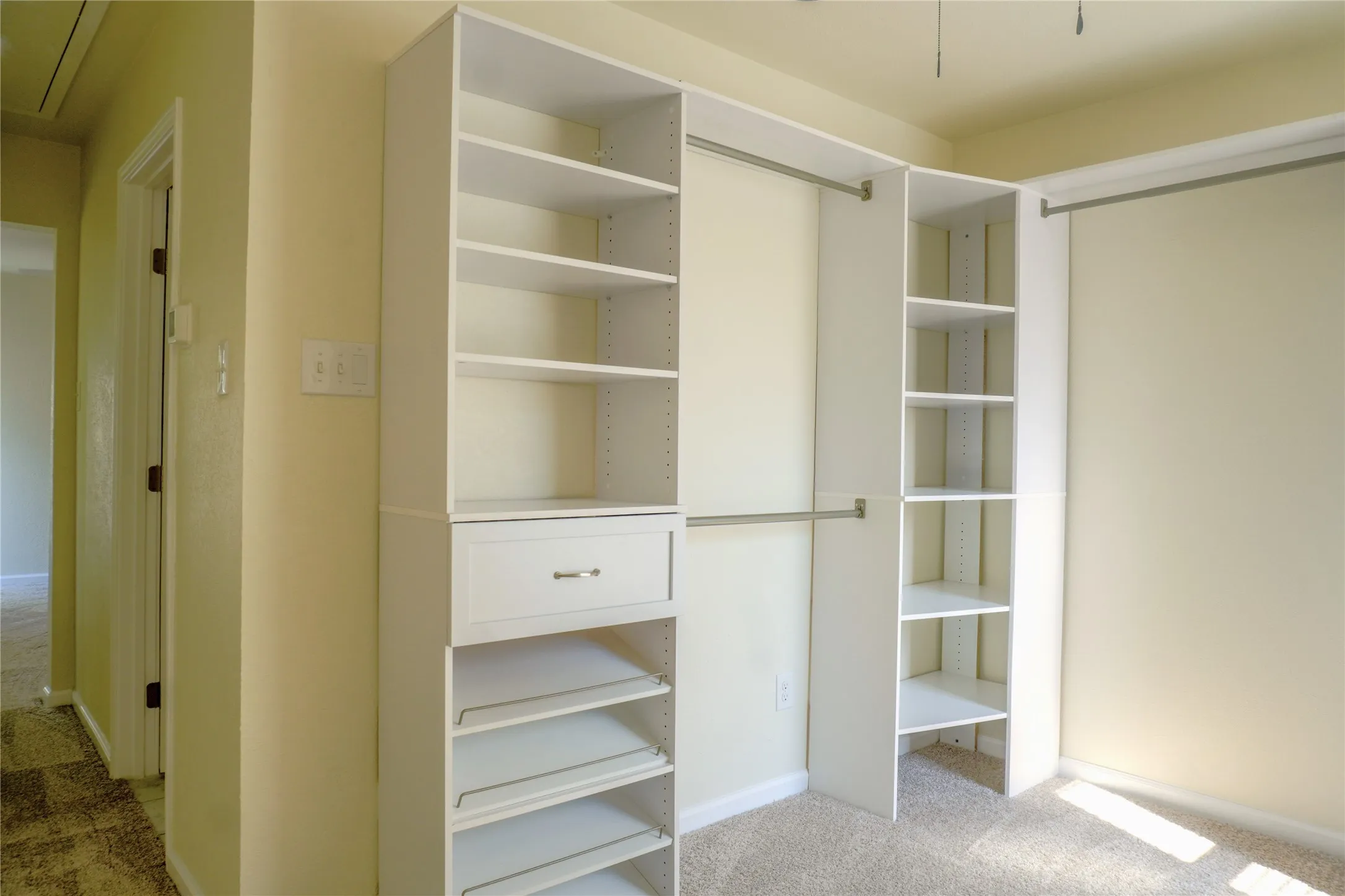 Custom closet system with multiple shelving units, garment rods, a pull-out drawer, and slanted shoe racks