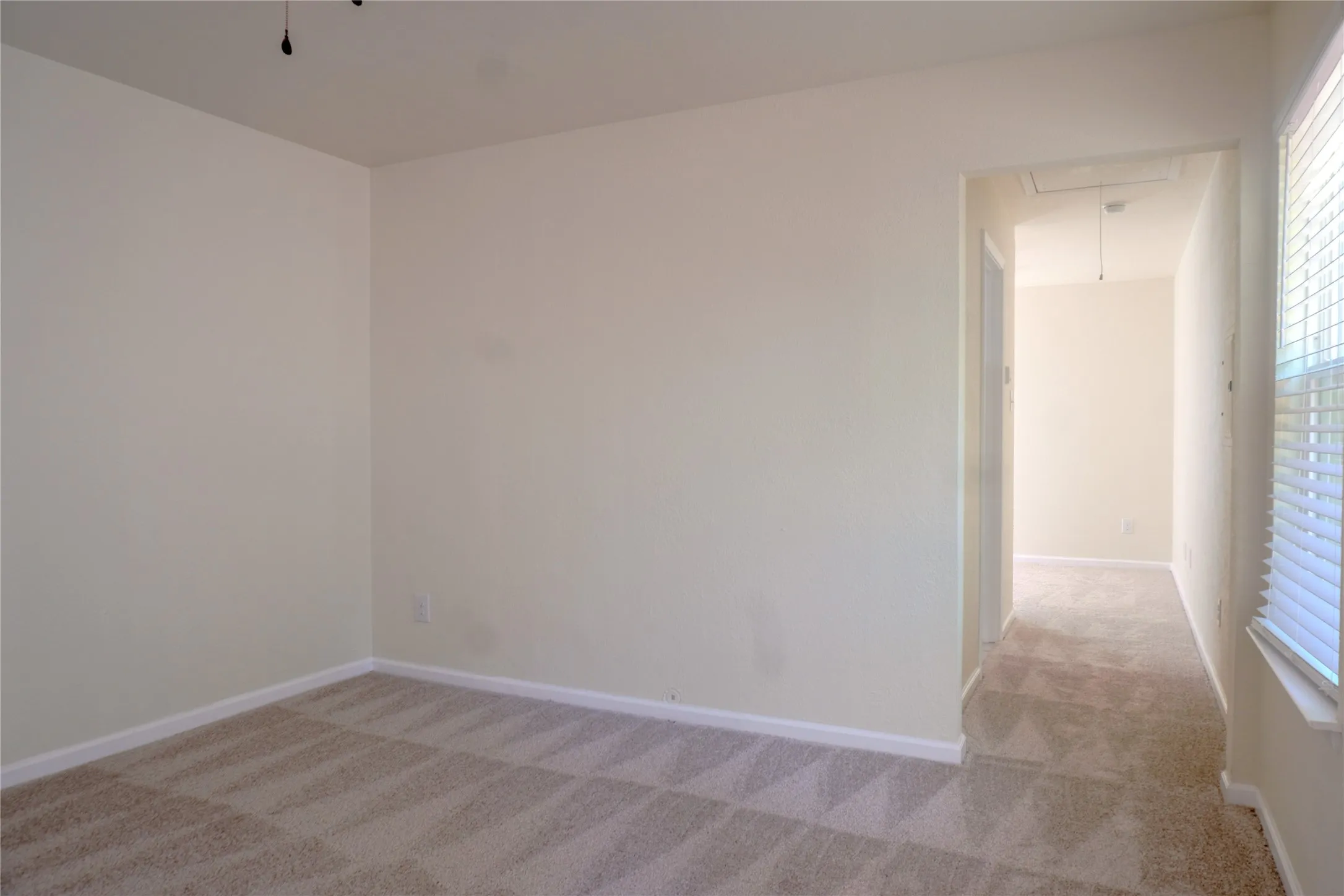 Neutral painted walls, carpeted flooring, white trim, and a window with blinds