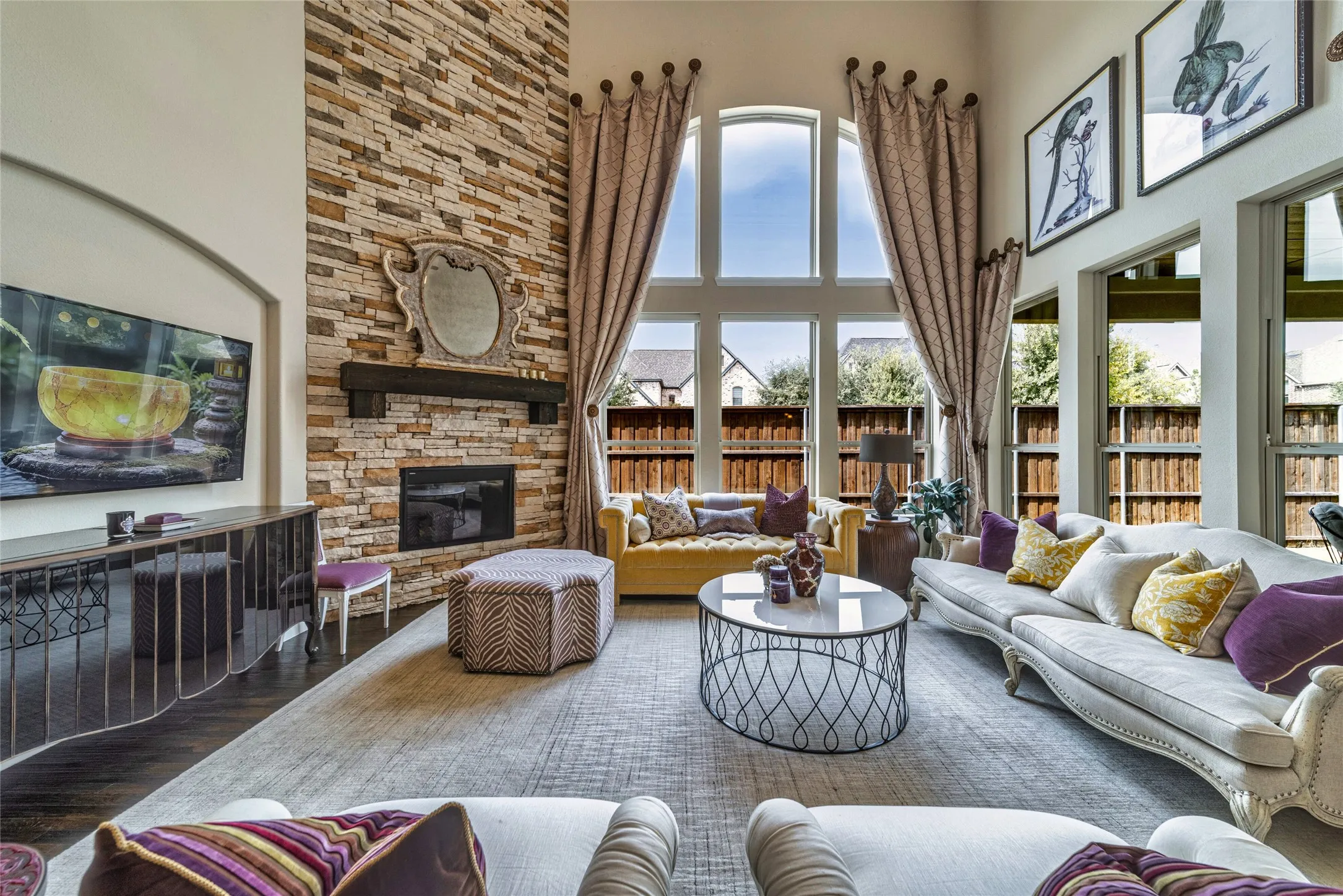 Soaring ceiling with a stacked stone fireplace and dark wood-finish mantel