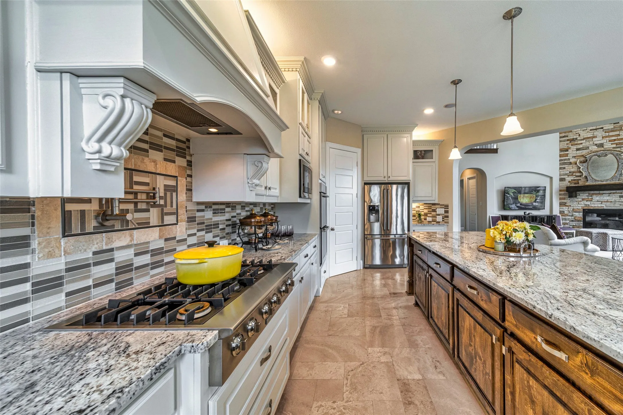 Gourmet kitchen featuring a built-in gas range, white cabinetry, a large kitchen island with wood-finish base, and stone countertops