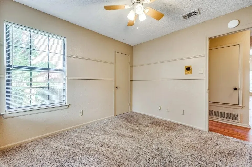Carpeted room with a ceiling fan, wall trim, and a window with blinds