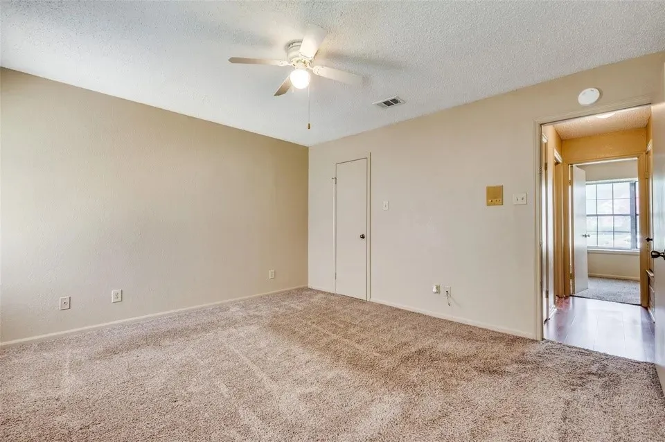 Wall-to-wall carpeting, ceiling fan with integrated lighting, and a neutral wall palette