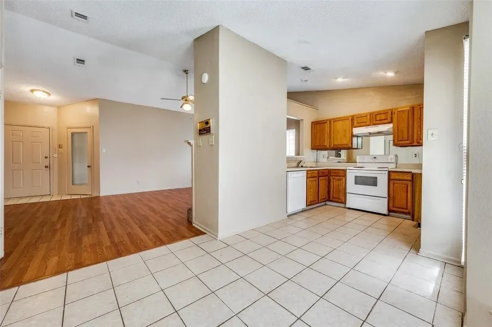 Kitchen featuring wood-finish cabinetry, white appliances, and tiled flooring