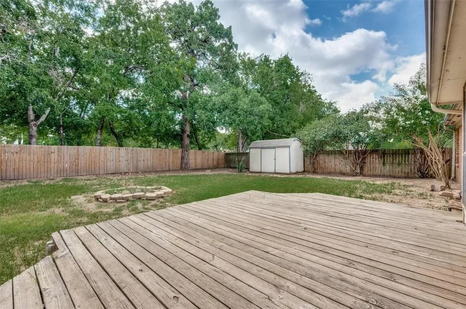 Wood deck with a stone-lined fire pit, a storage shed, and a wood privacy fence