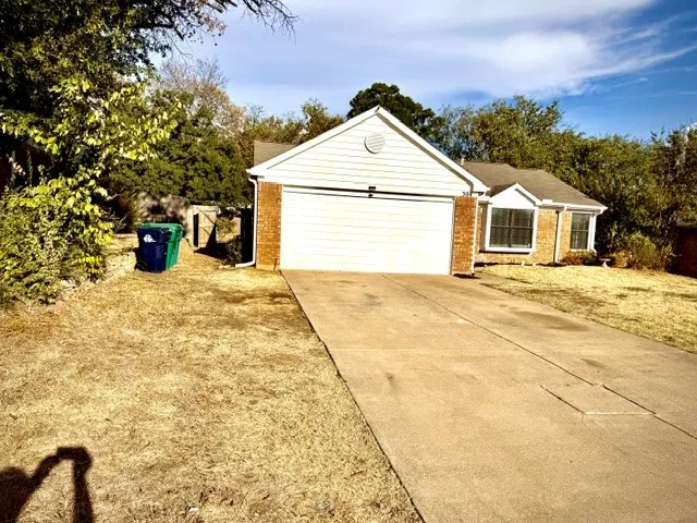 Brick and siding exterior, front-facing attached garage, concrete driveway, and mature landscaping