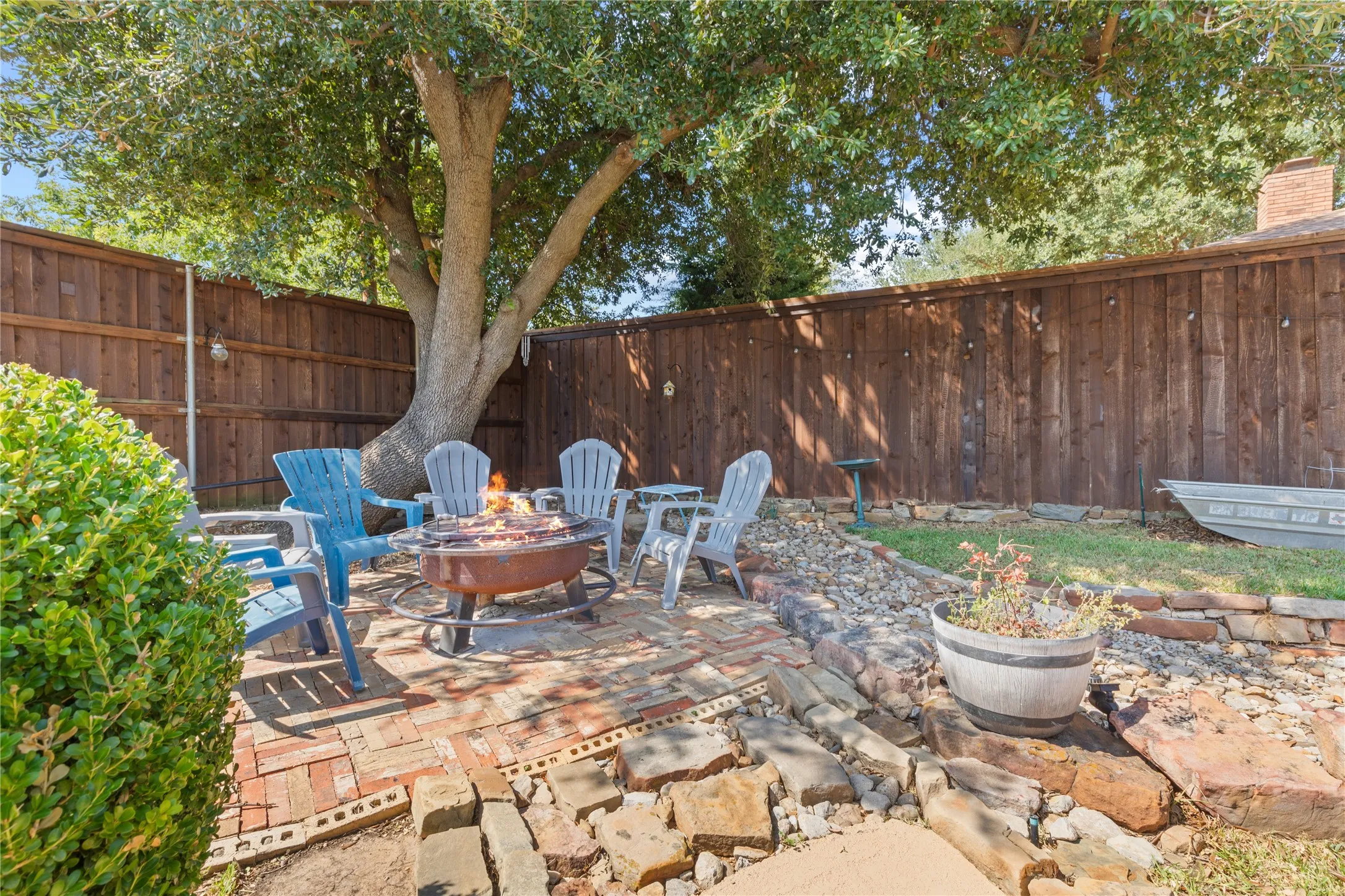 Backyard patio with brick hardscaping, a stone fire pit, and privacy fencing