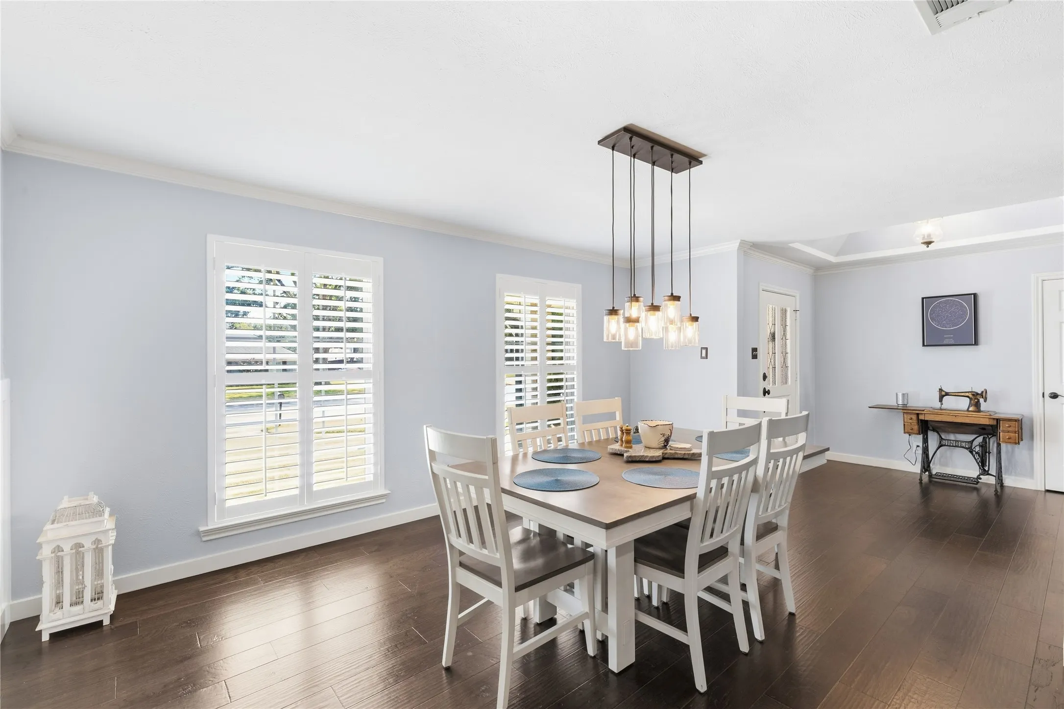 Wood-finish flooring throughout, white plantation shutters, built-in recessed lighting, and a multi-pendant light fixture with glass shades