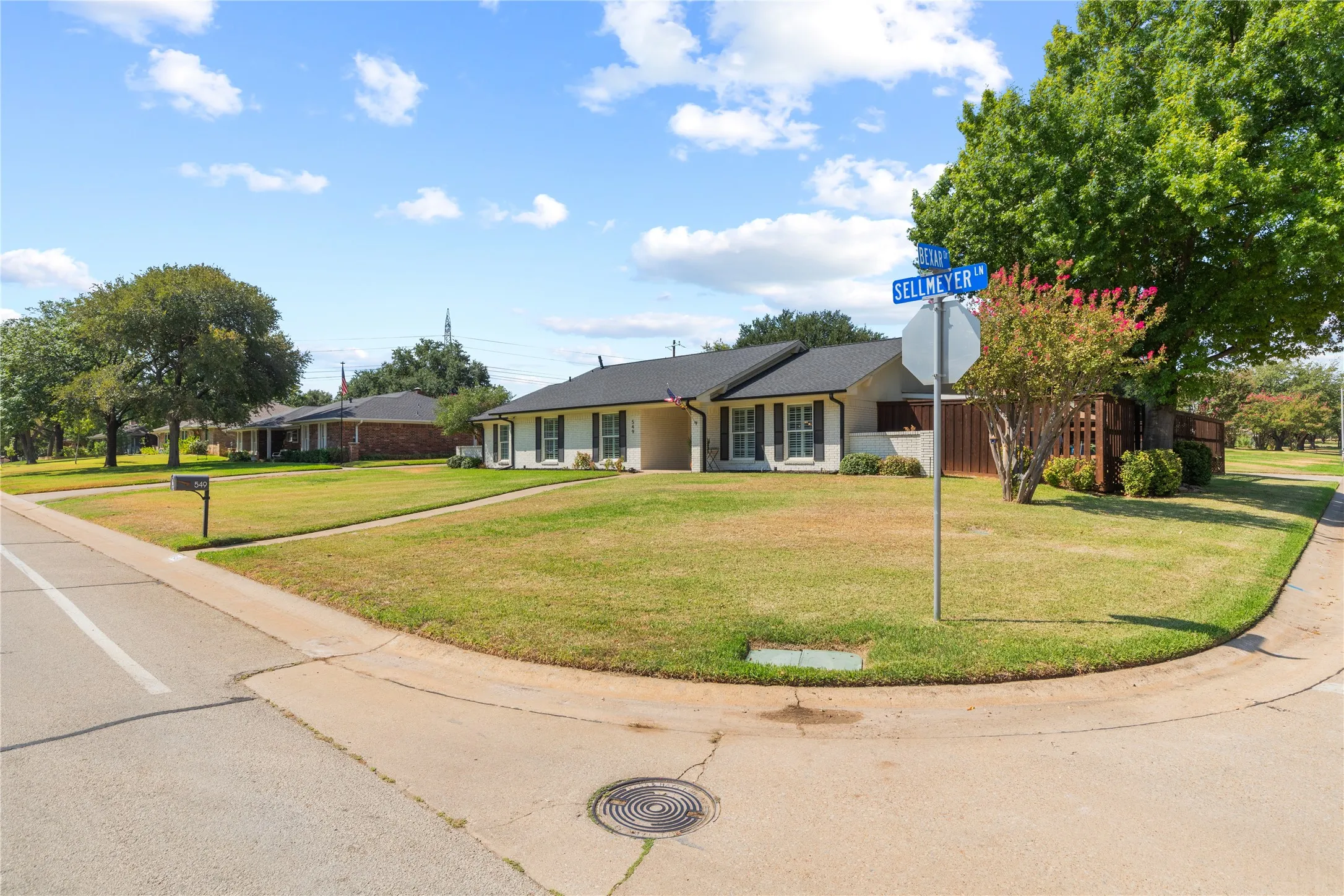 Corner lot property featuring a white exterior, black shutters, a dark roof, and a fenced side yard
