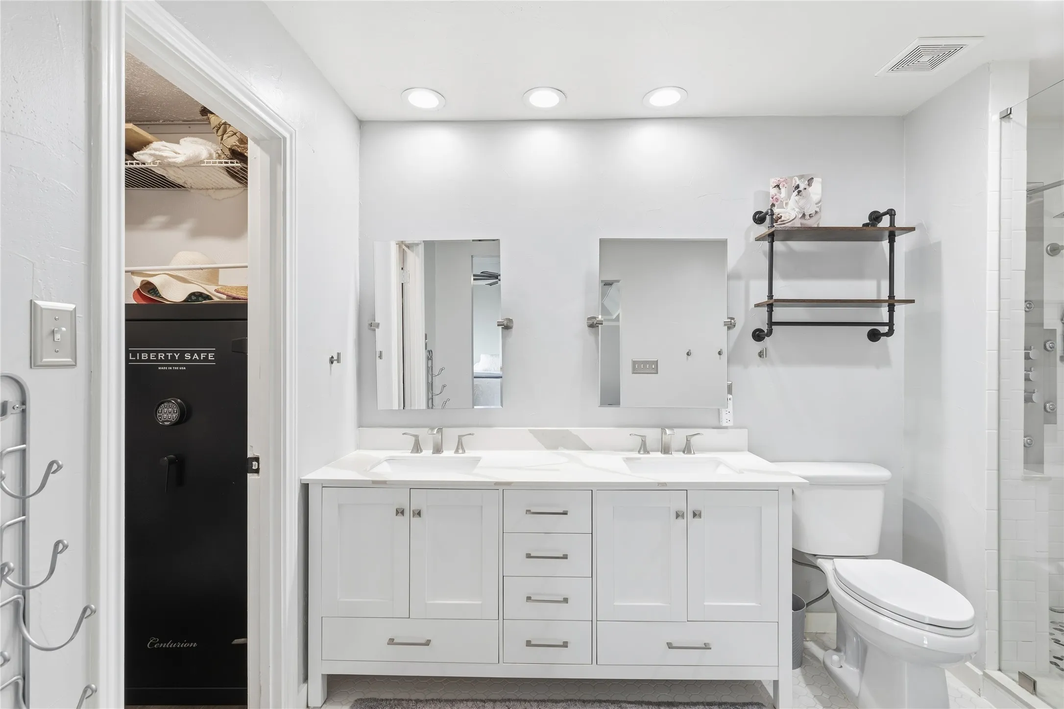 Recessed lighting, dual vanity with white cabinetry, white countertops, dual rectangular sinks, and an industrial-style wall-mounted shelving unit