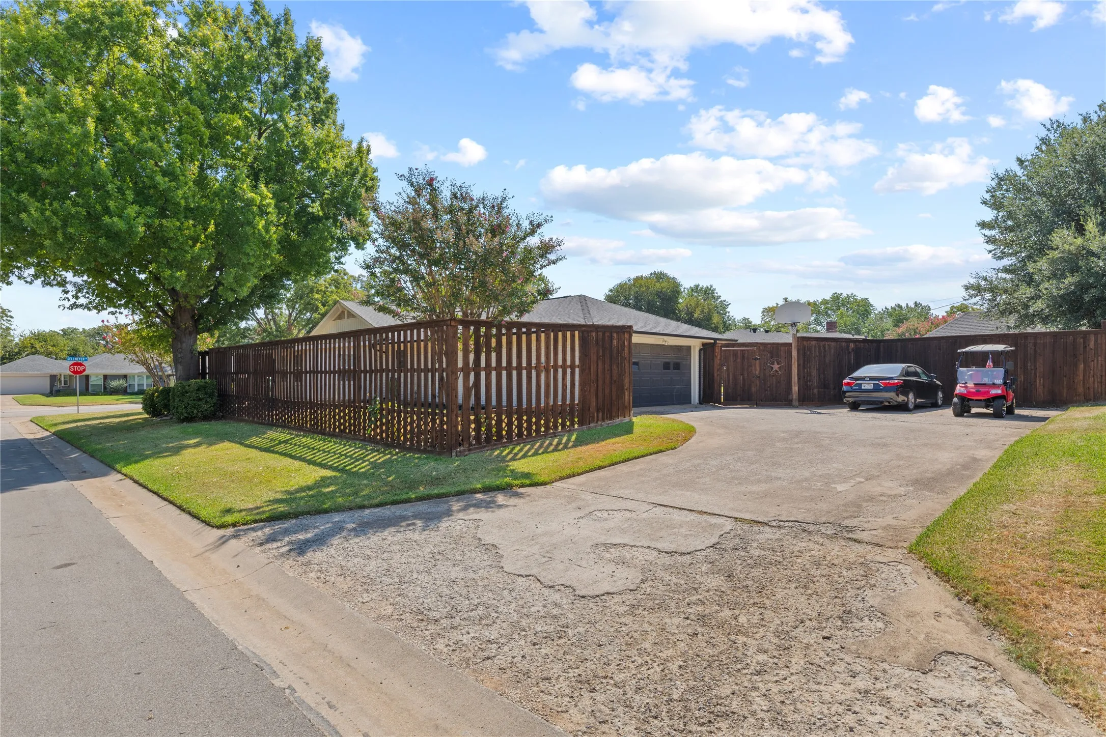 Expansive paved driveway, attached two-car garage, and privacy fencing