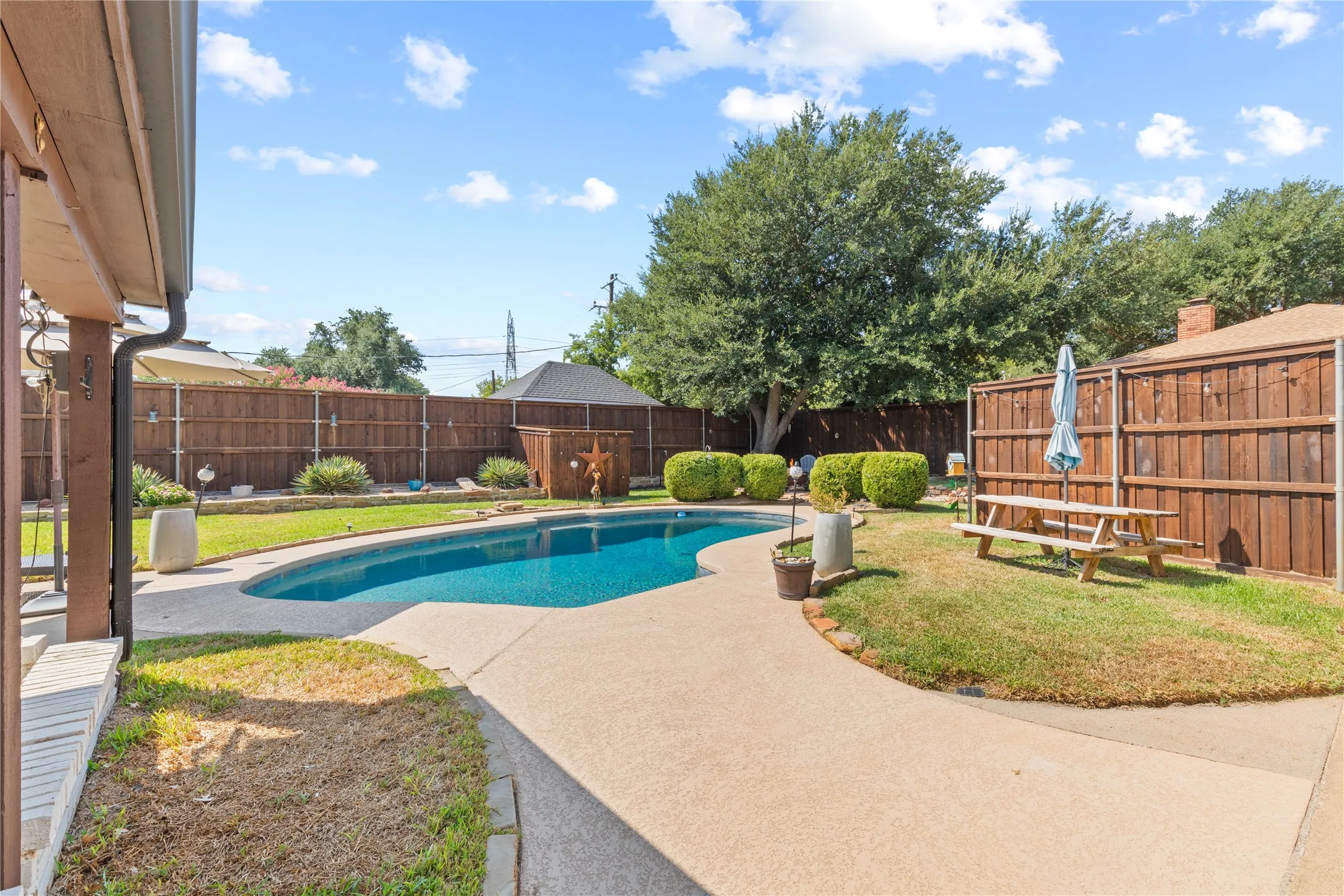 Backyard featuring an in-ground swimming pool, concrete decking, and a wood privacy fence