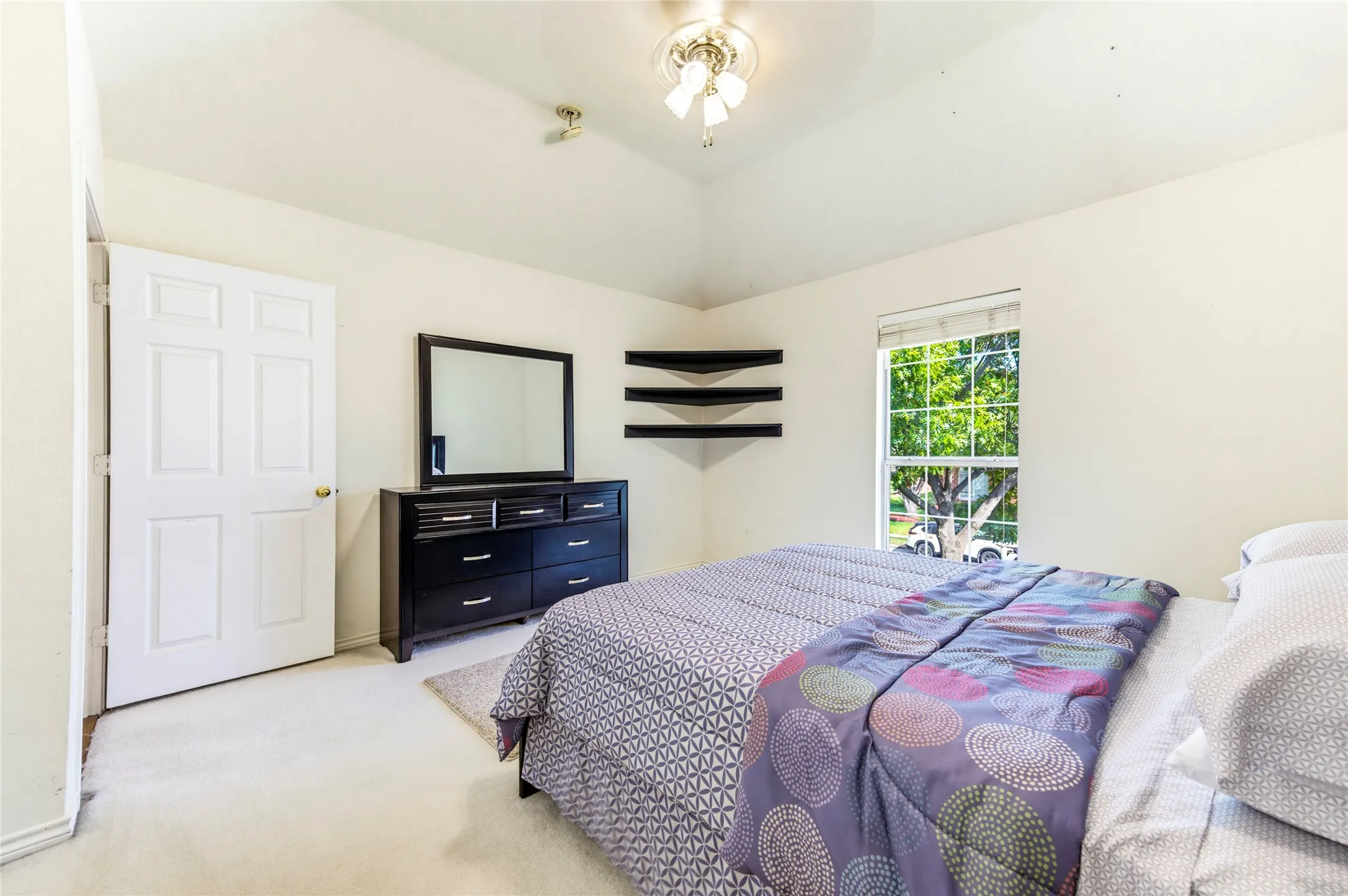Vaulted ceiling with an attached ceiling fan, single window with blinds, and light-toned carpeting...