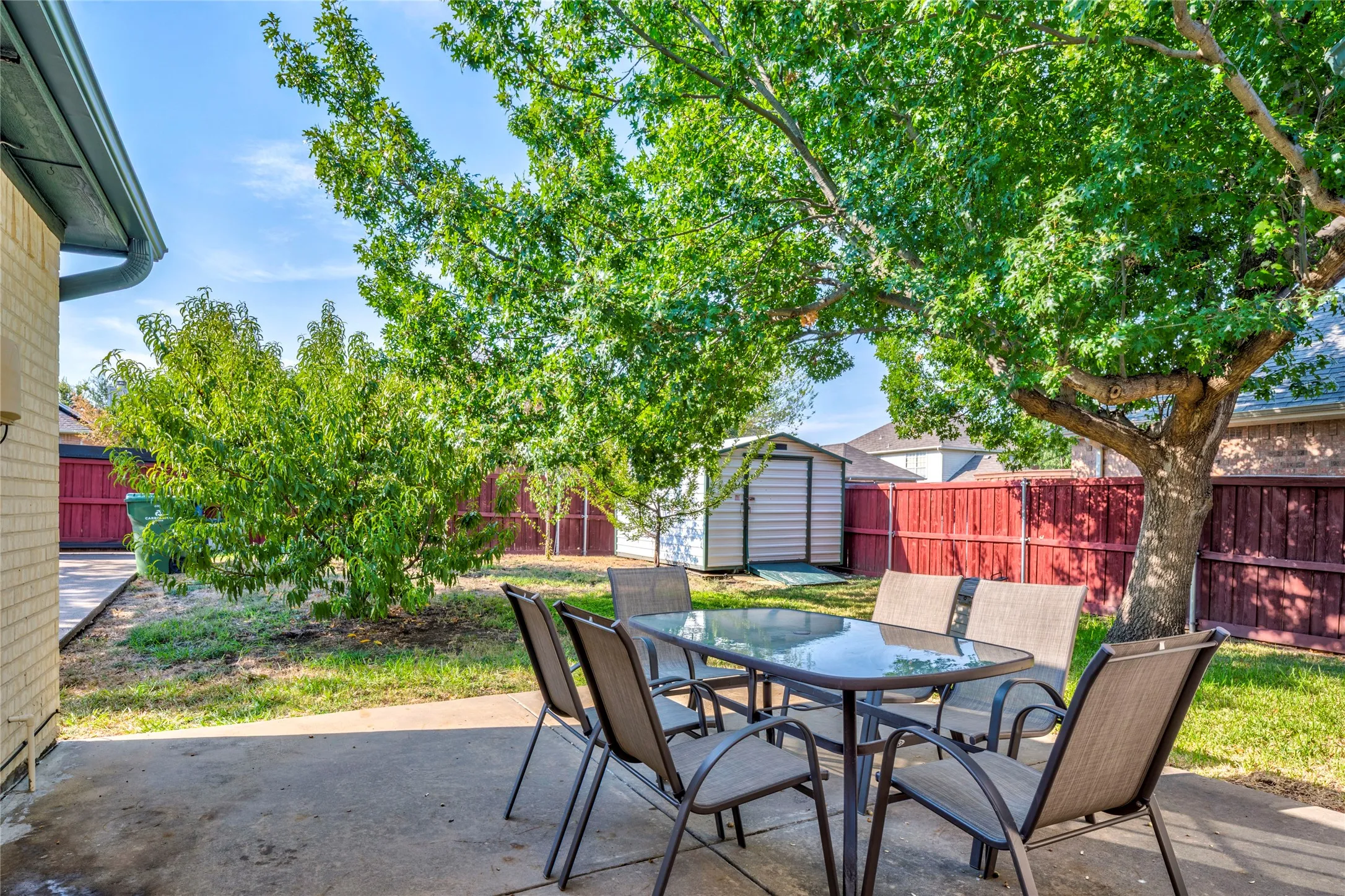 Great shaded concrete patio, mature trees, a storage shed, and wood fencing....