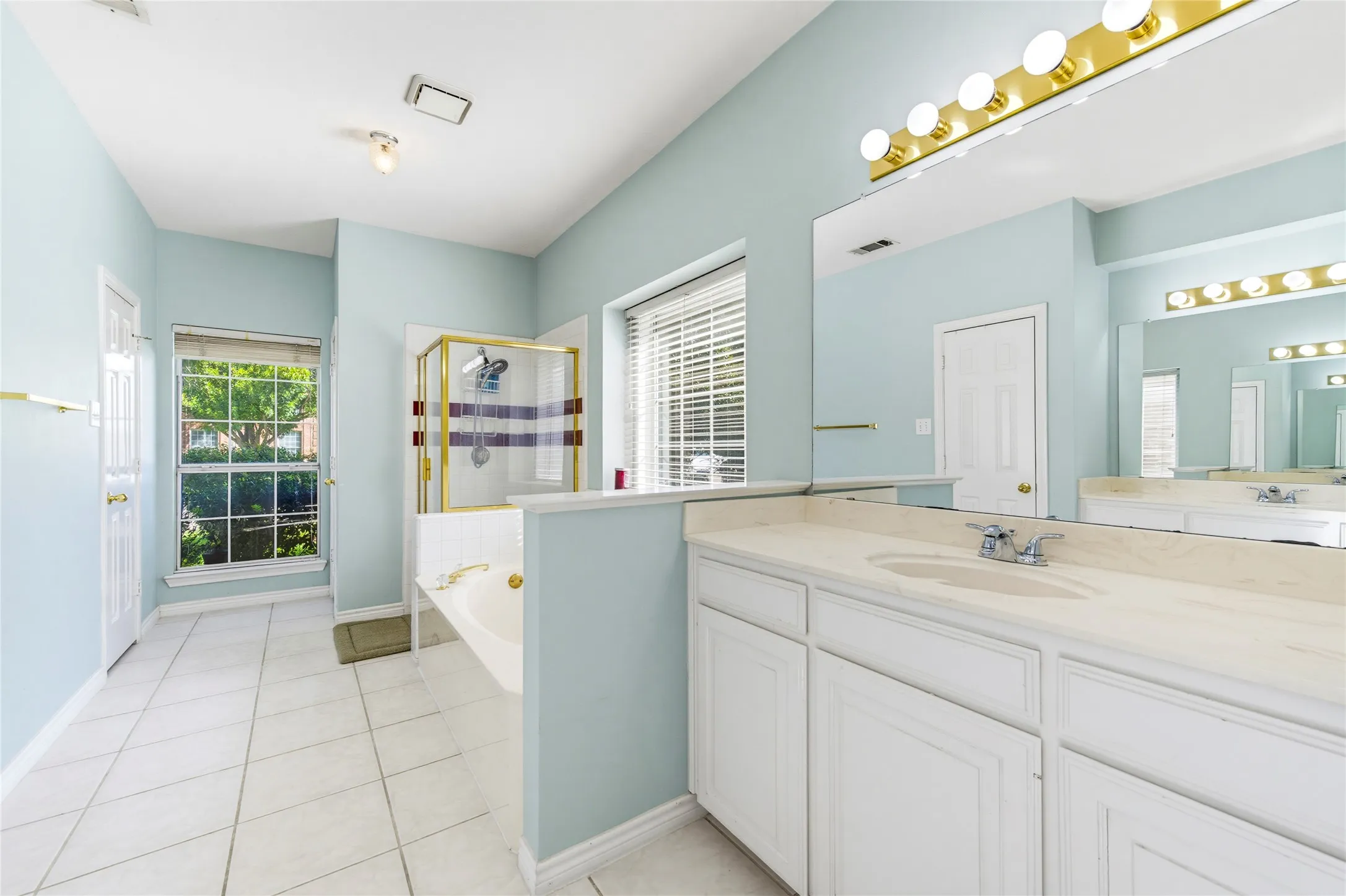 Dual vanities with integrated sinks, white cabinetry, and a large mirror, for either person....