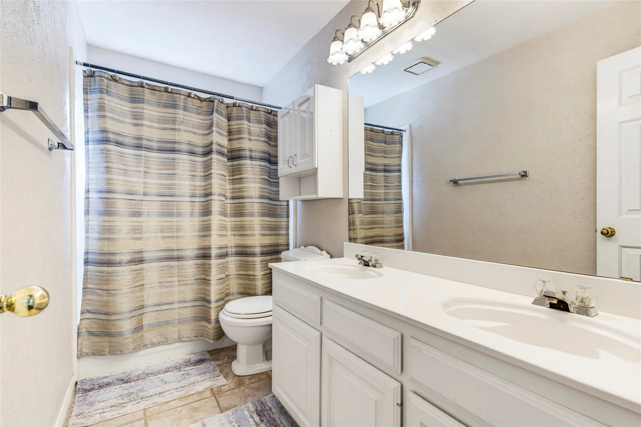 Dual vanity with integrated sinks, ample countertop space, full-width mirror, and white cabinetry