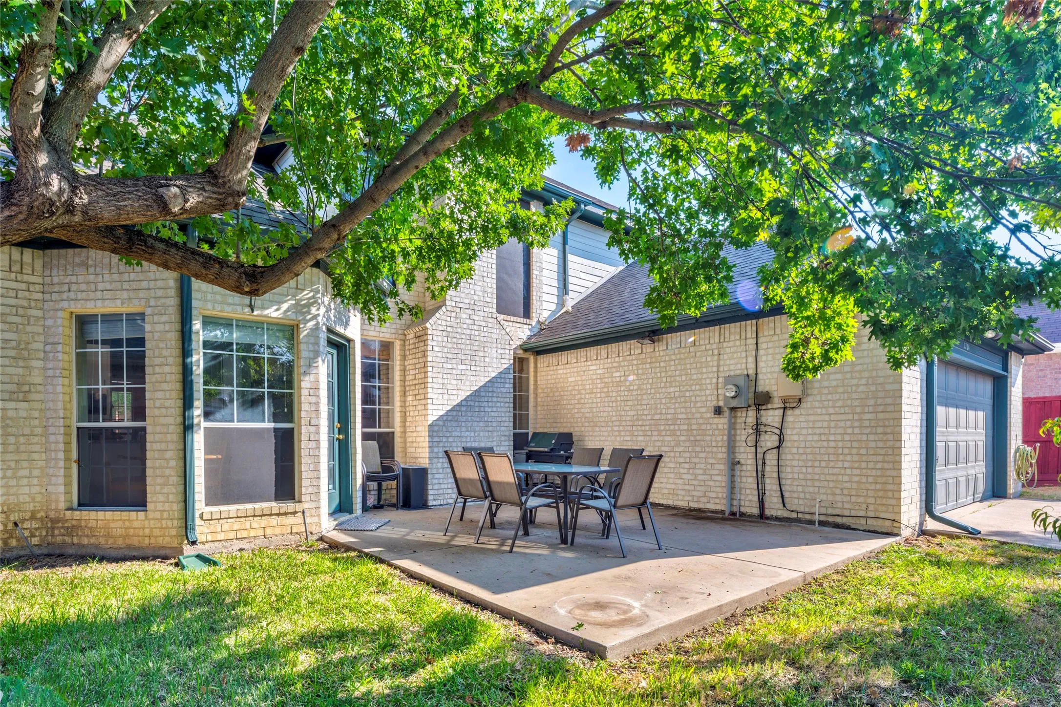 Expansive concrete patio with brick exterior and attached garage