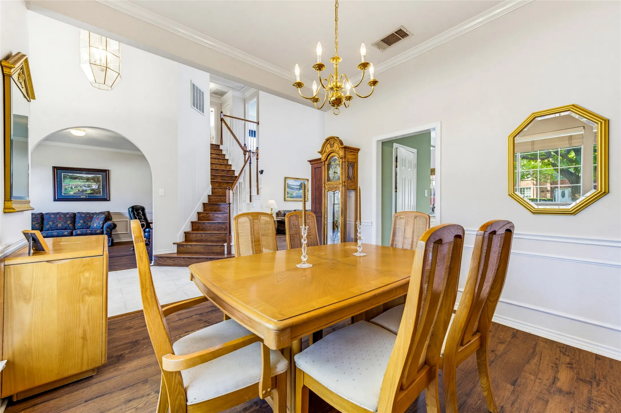 Dining room looking into the entry and archway entry into the office. Beautiful wood staircase. Wood like laminate flooring, crown molding, chair rail molding in dining room....