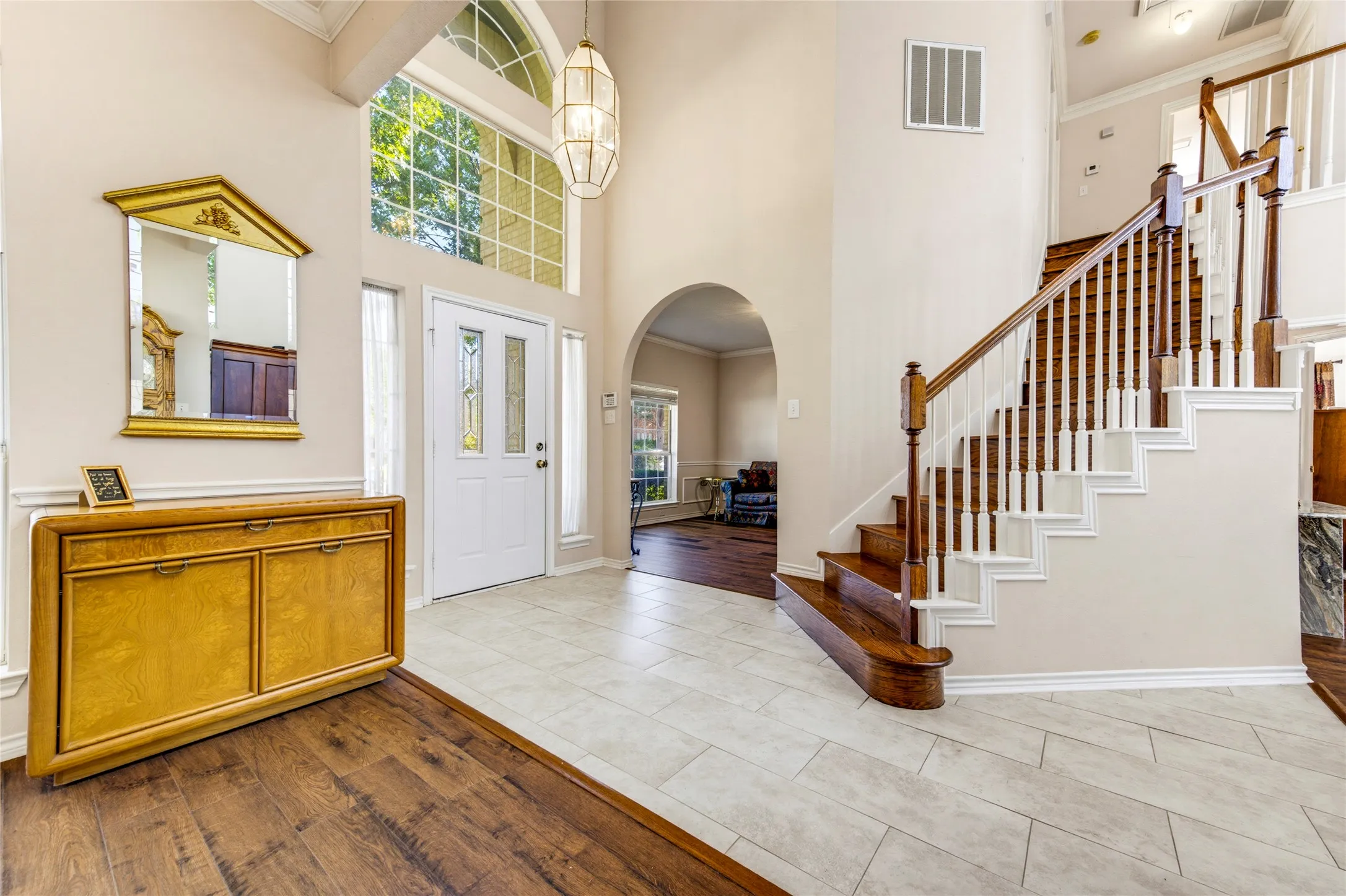 Two-story foyer featuring a grand staircase with wood treads and white risers, an arched entryway, a transom window, and tile flooring.....