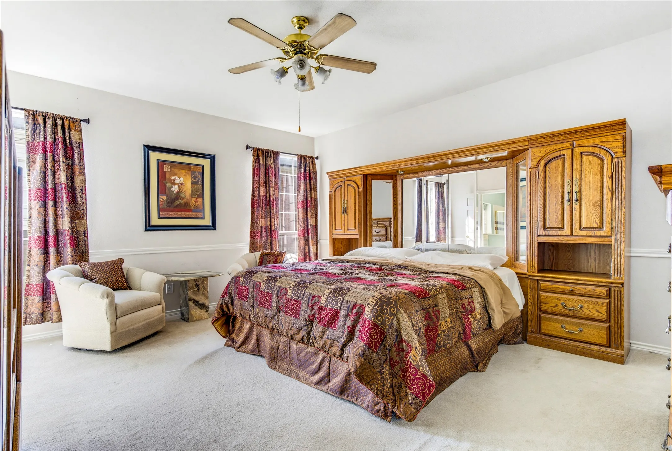 Spacious primary bedroom, light-colored carpeting and a ceiling fan.....