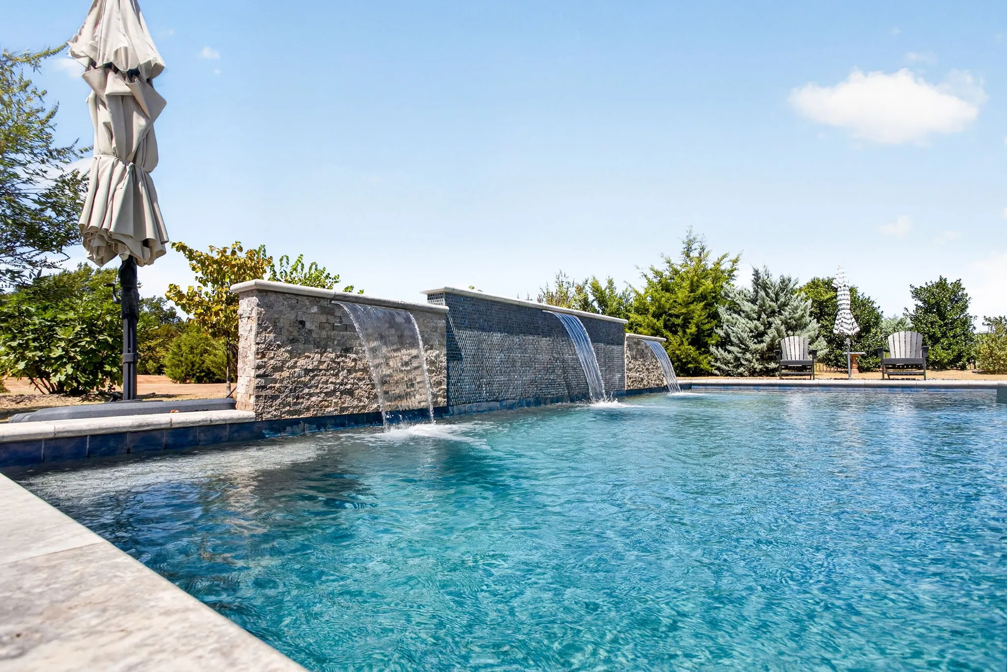 Swimming pool with stone-clad water features and integrated spa area