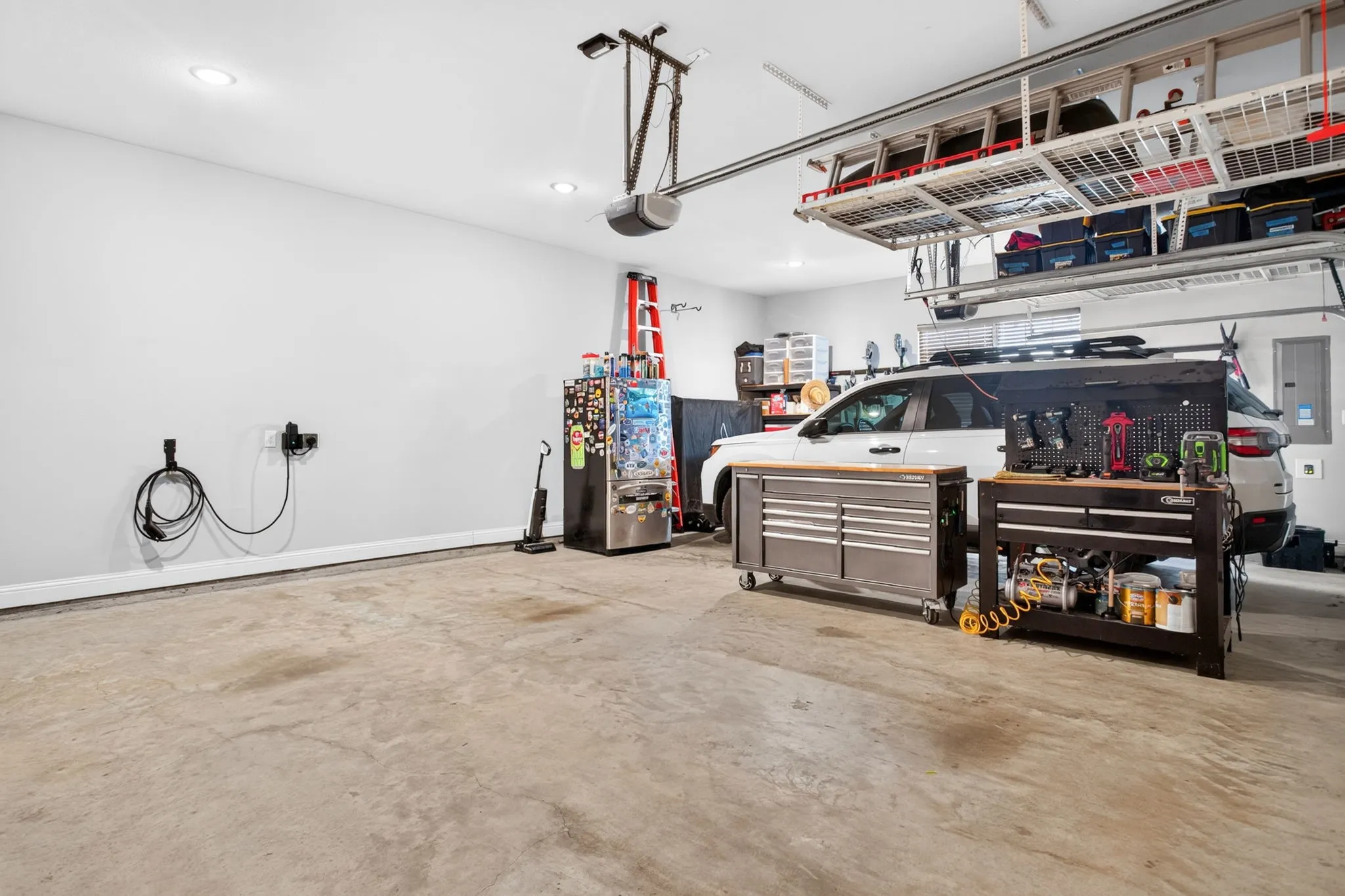 Garage with recessed lighting, overhead storage racks, and a wall-mounted charging station