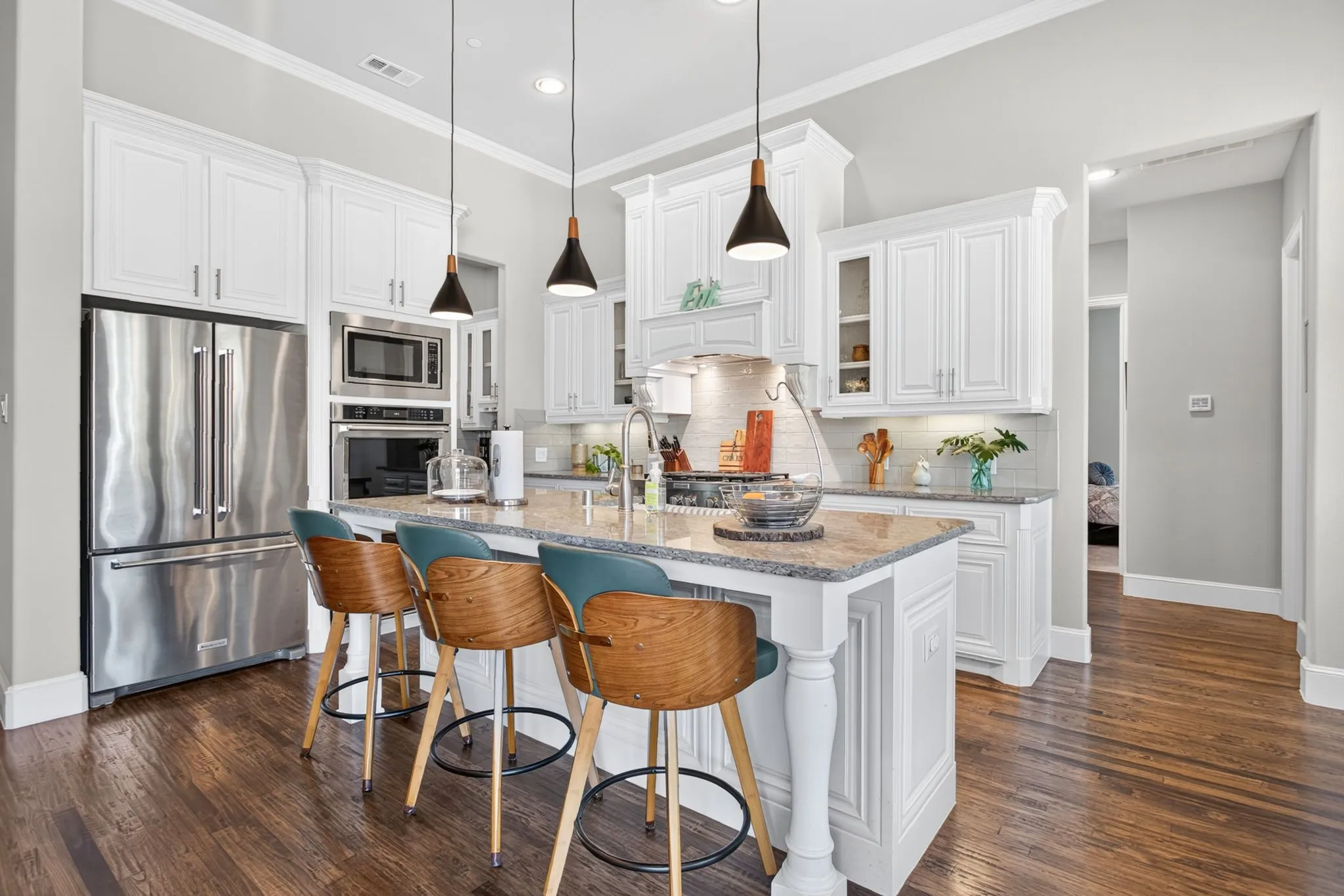 Contemporary kitchen featuring white cabinetry, stainless steel appliances, and a quartz-topped island with seating for three