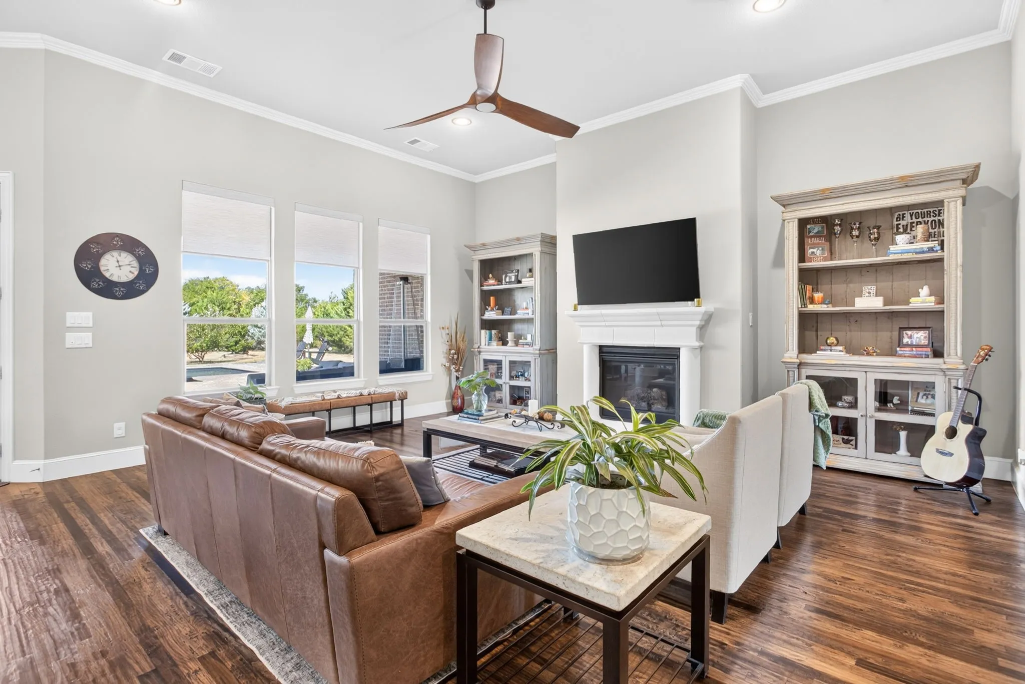 Hardwood flooring, crown molding, tall ceilings, recessed lighting, and a fireplace with a mantel
