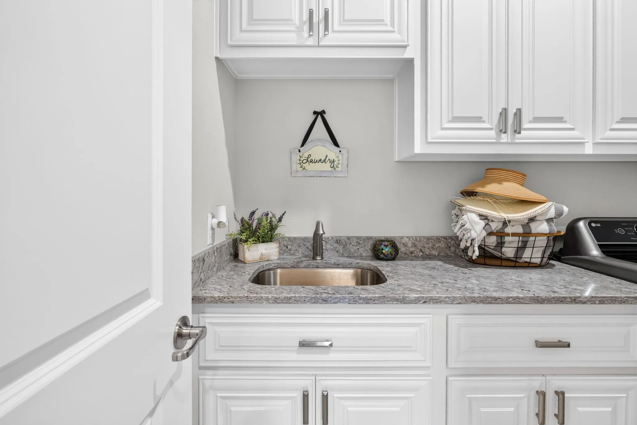 White shaker cabinetry, granite-style countertop, stainless steel sink, and brushed nickel hardware